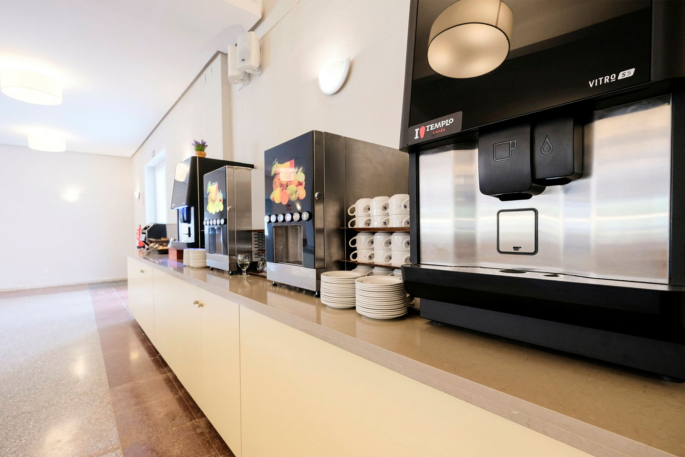 En opstilling med kaffemaskiner, stablede kopper og tallerkener. (AI-genereret tekst)