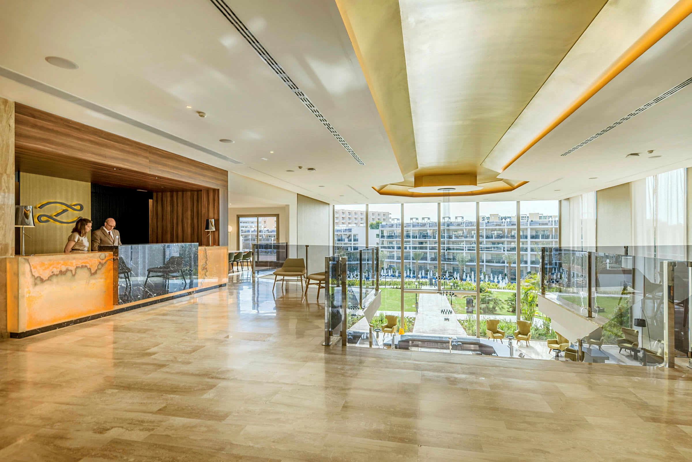 Elegant hotellobby med reception og store vinduer, der vender ud mod en frodig udsigt. (AI-genereret tekst)