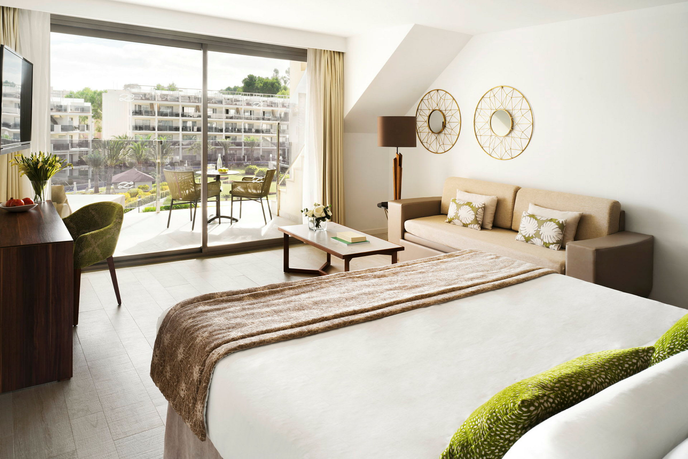 Et lyst hotelværelse med en seng, en sofa og en balkon udenfor. (AI-genereret tekst)
