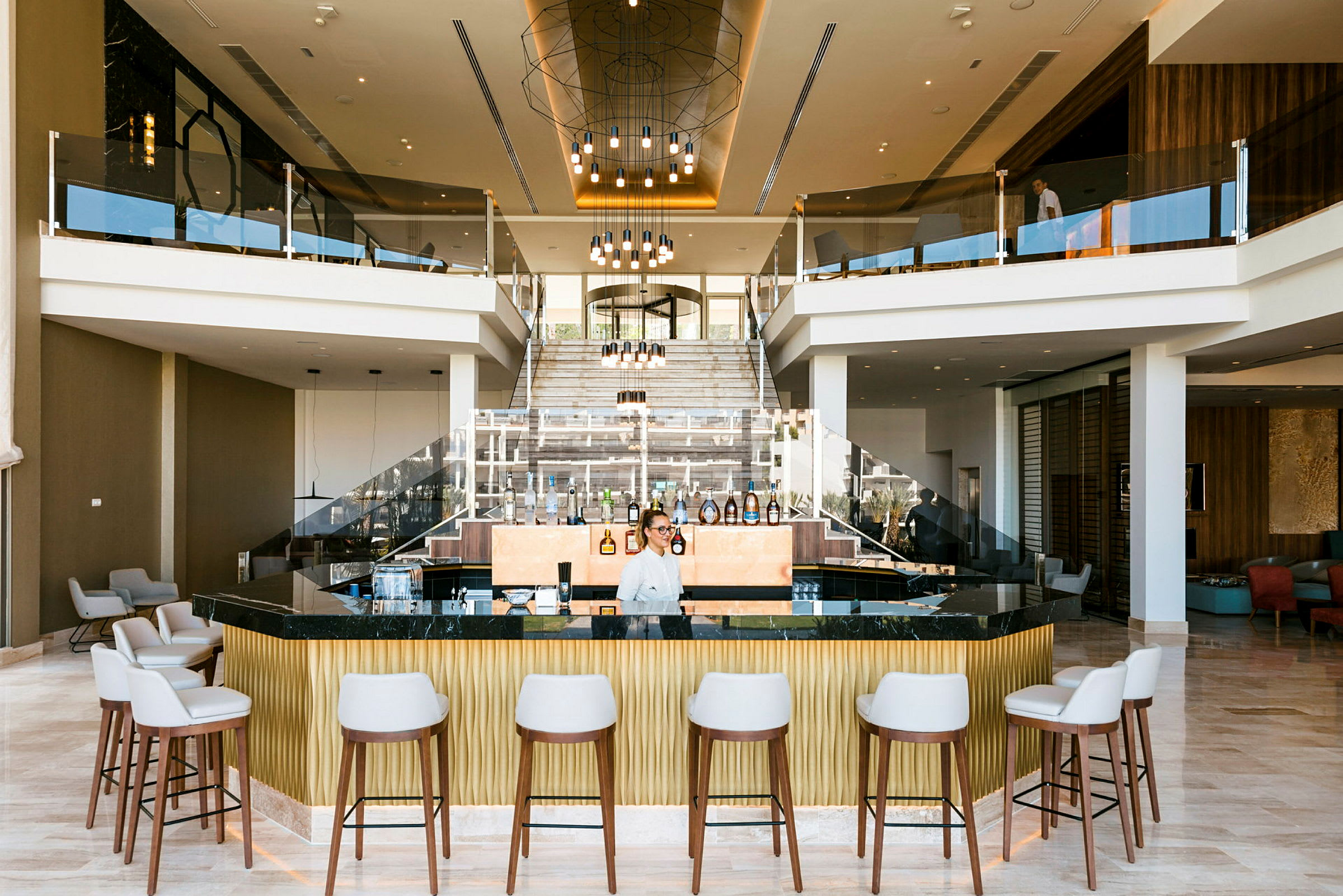 En hotel lobby med en moderne bar, siddeområder og en central trappe. (AI-genereret tekst)