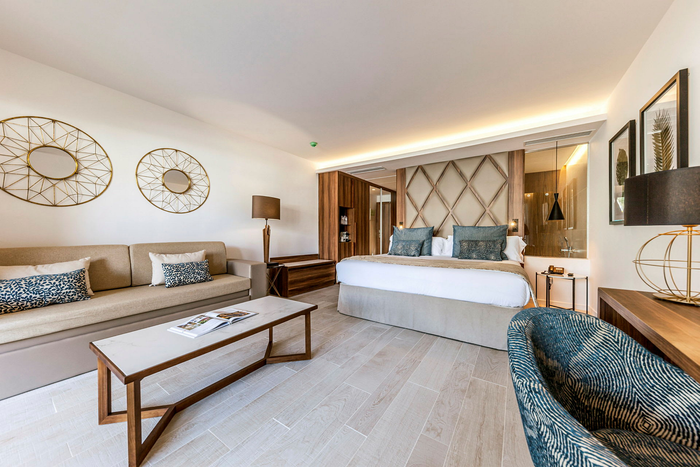 Et elegant hotelværelse med en dobbeltseng, en sofa, et sofabord og moderne indretningselementer. (AI-genereret tekst)