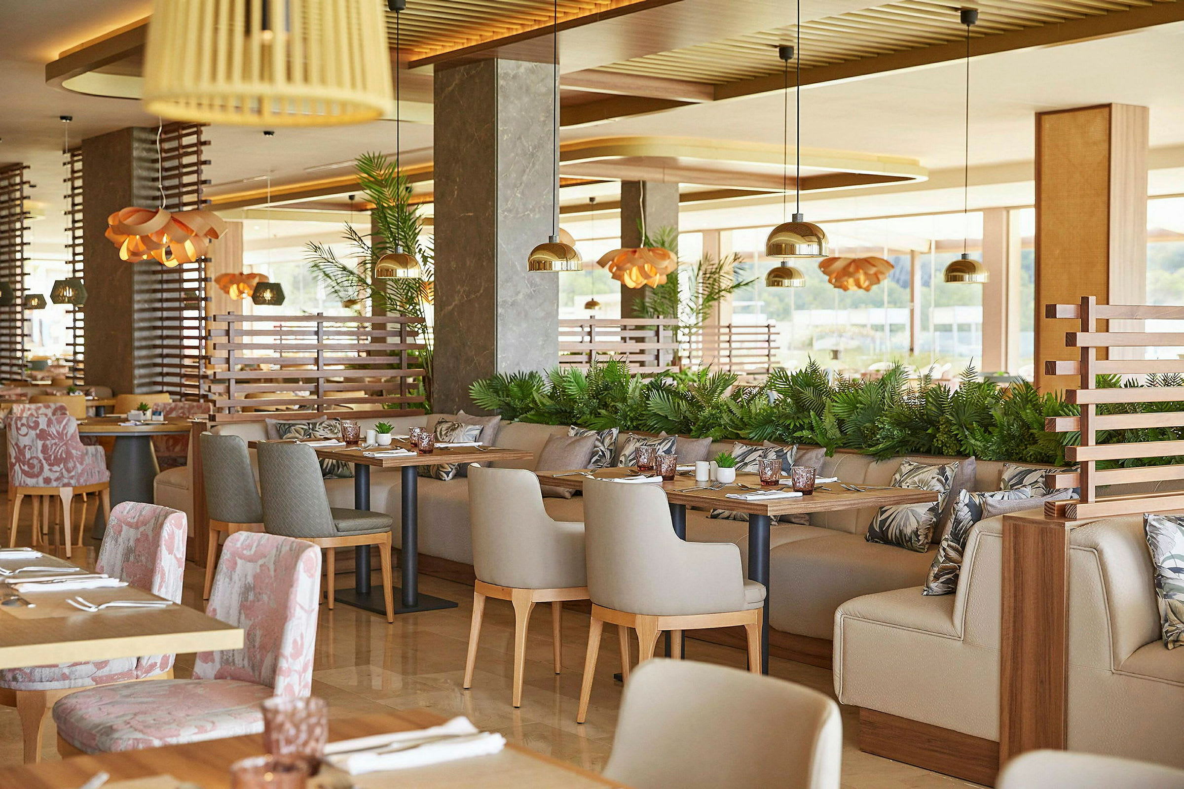 Et moderne og elegant indrettet restaurantområde med borde og stole, dekoreret med planter og belysningsdetaljer. (AI-genereret tekst)