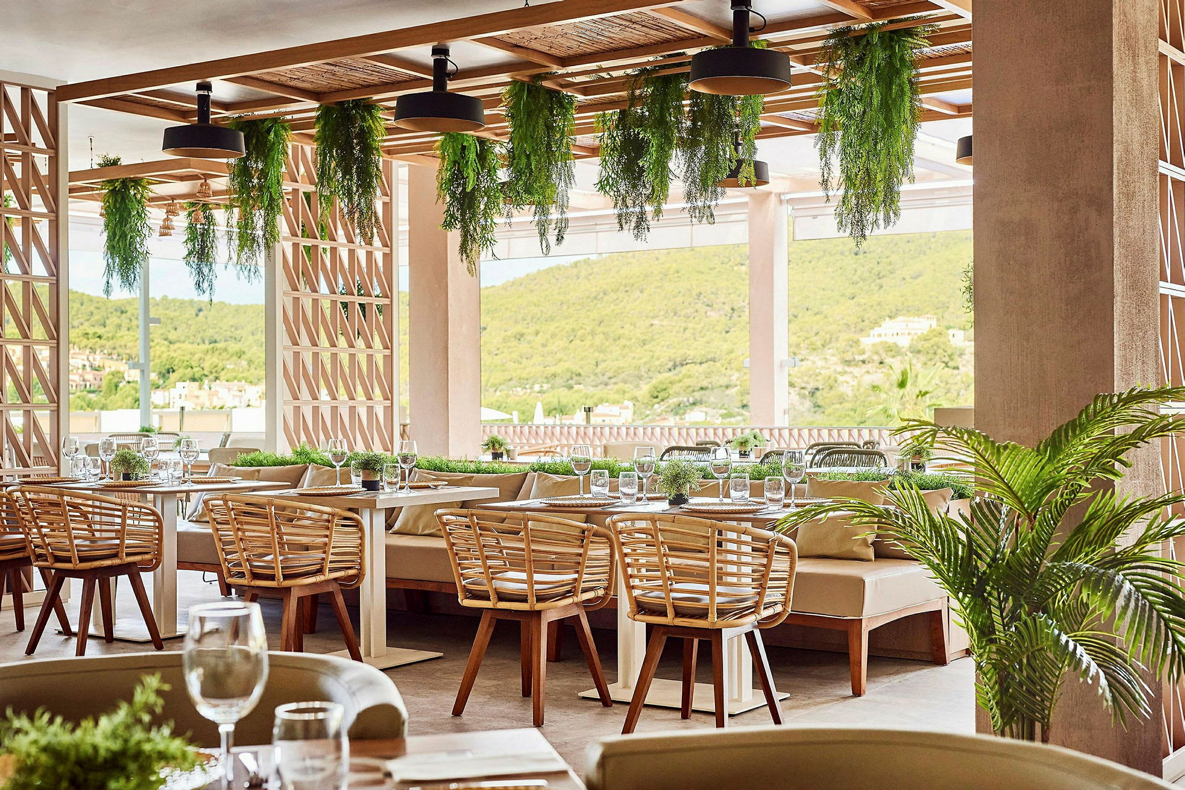 En restaurant med borde, træstole og planter hængende fra loftet. (AI-genereret tekst)