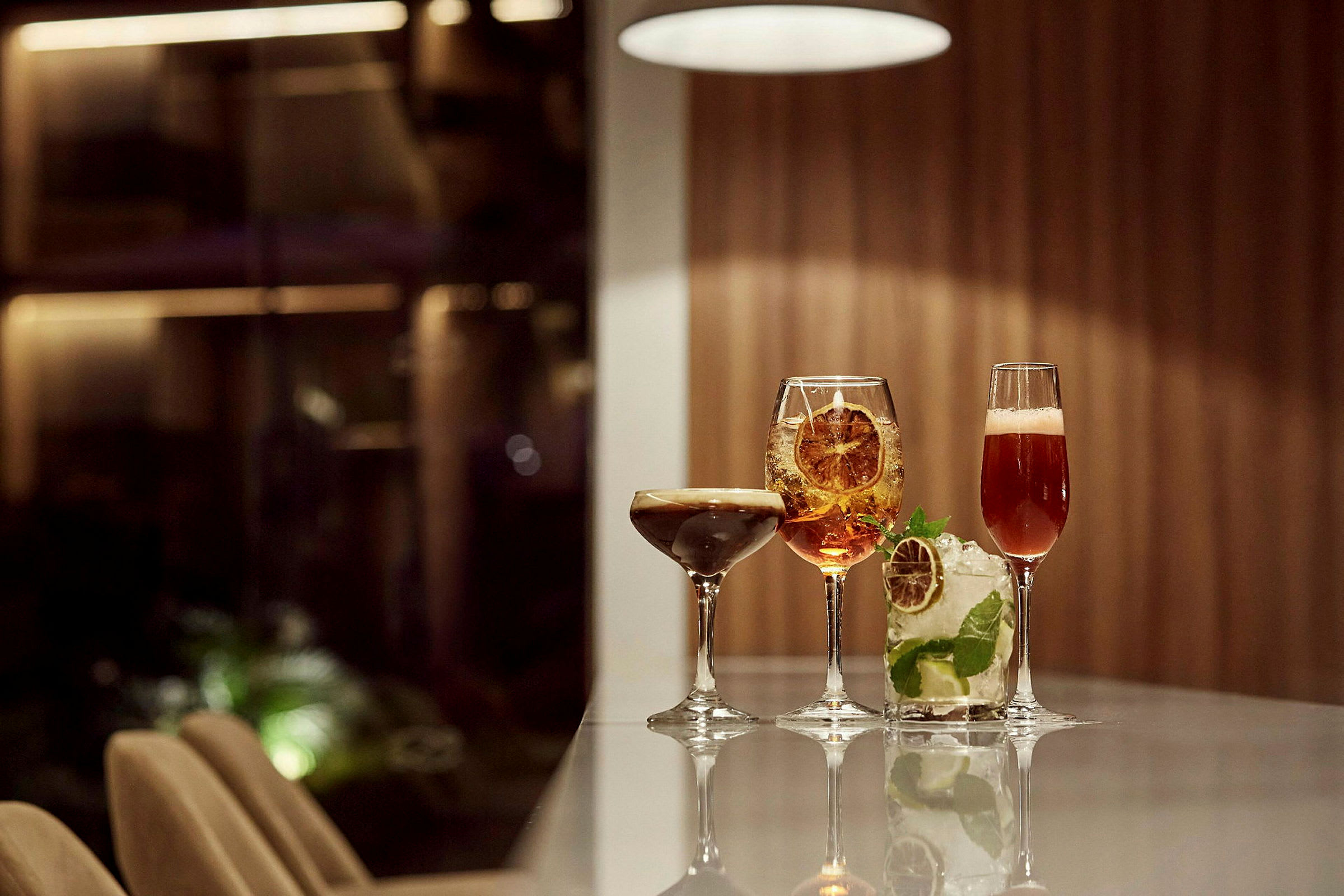 Fire cocktails på et bord i et elegant miljø. (AI-genereret tekst)