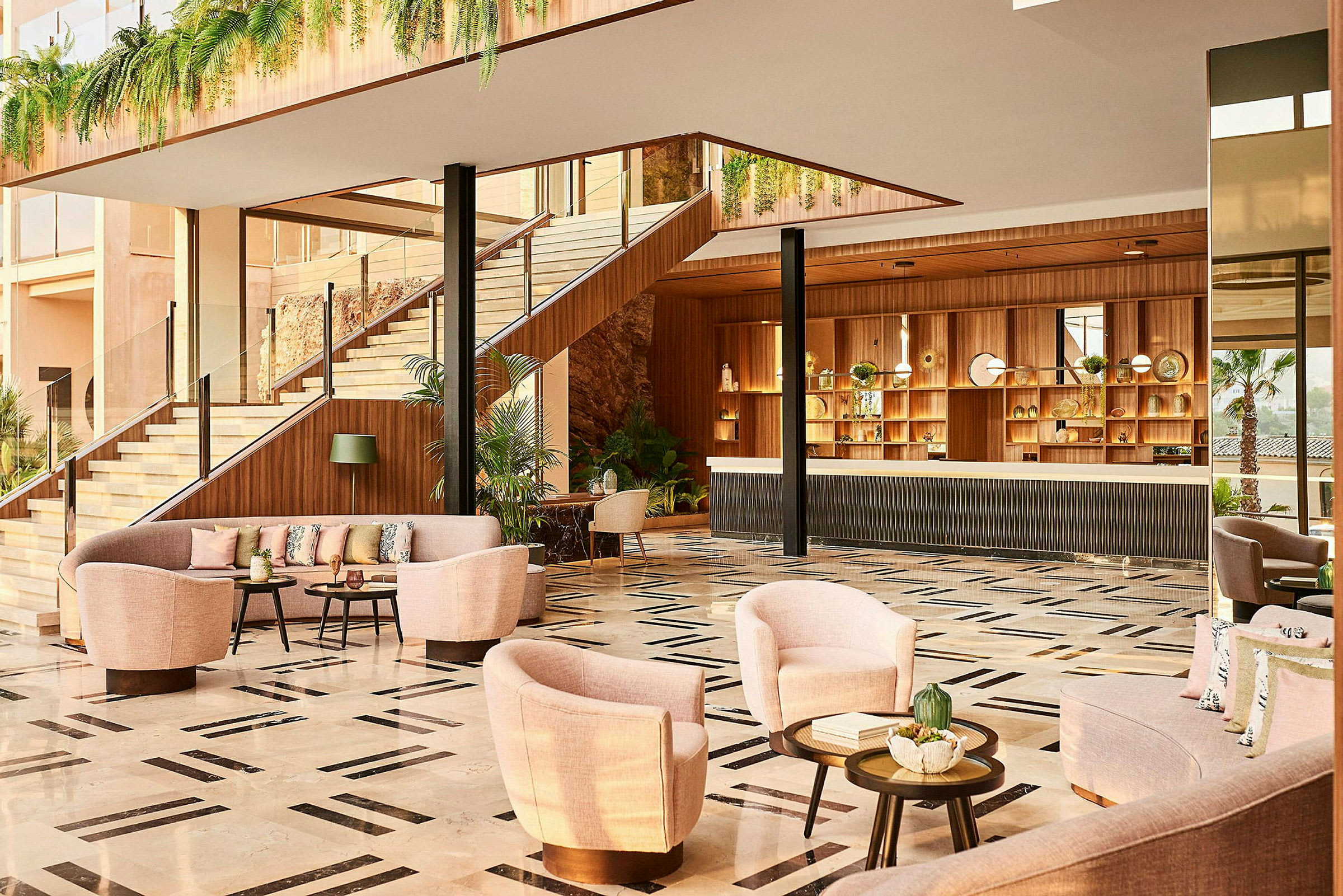 En hotellobby med sofaer og lænestole, en reception og trappe omgivet af planteindretning. (AI-genereret tekst)