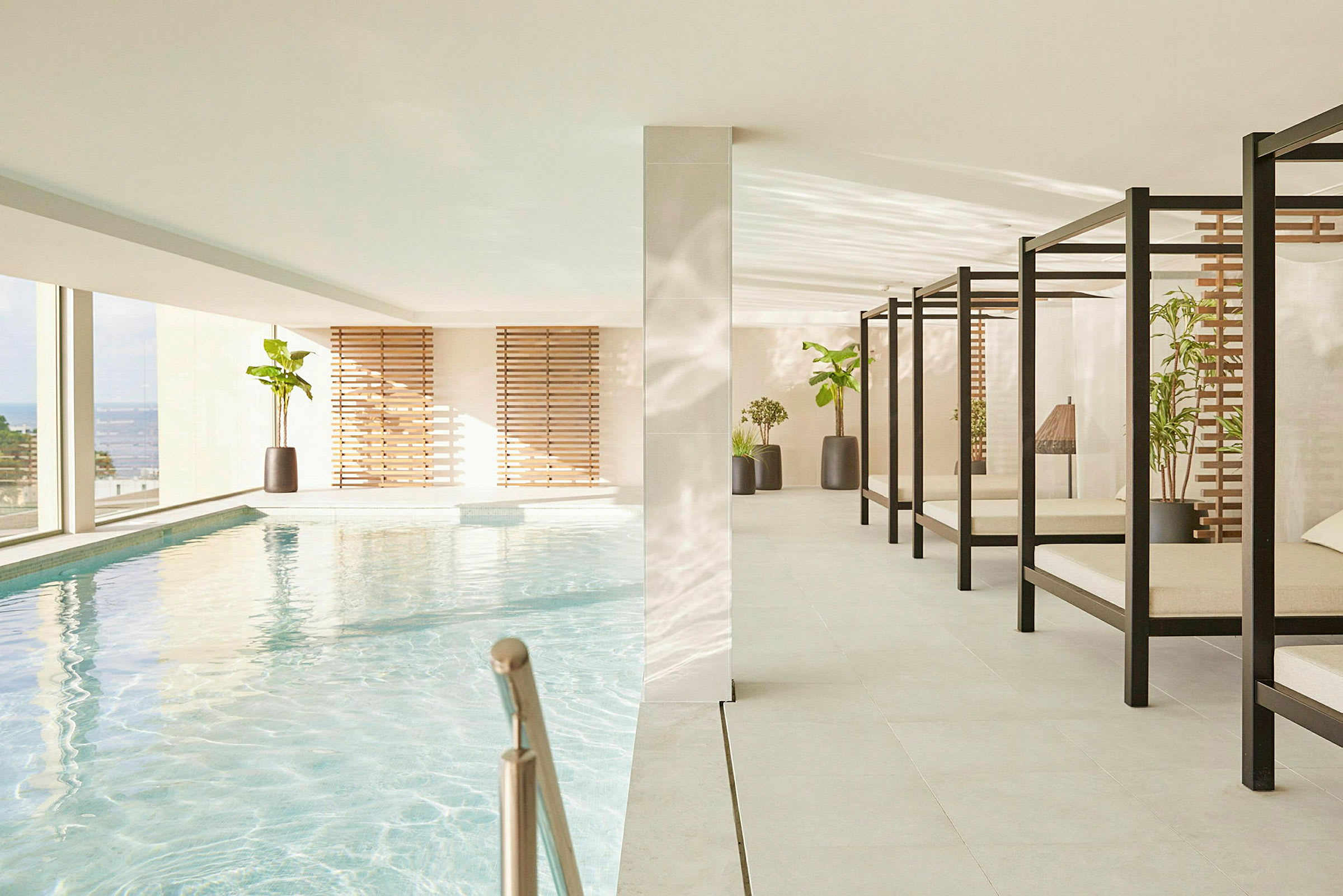 En indendørs swimmingpool med behagelige liggestole og planter ved siden af. (AI-genereret tekst)