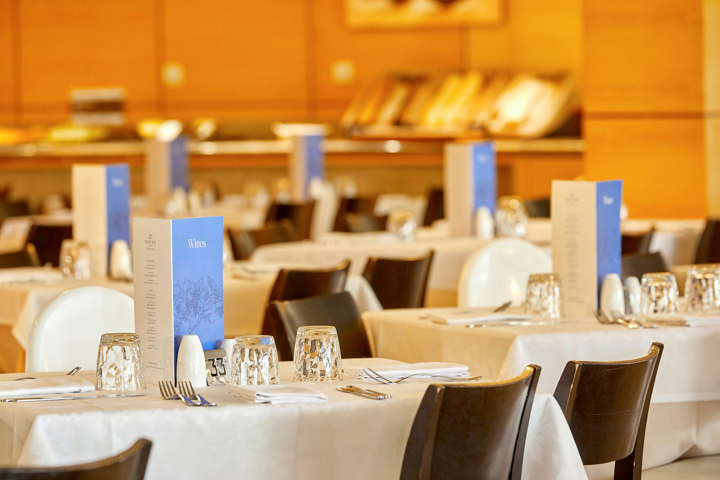 Billede af dækkede borde i en restaurant med menukort placeret på hvert bord. (AI-genereret tekst)