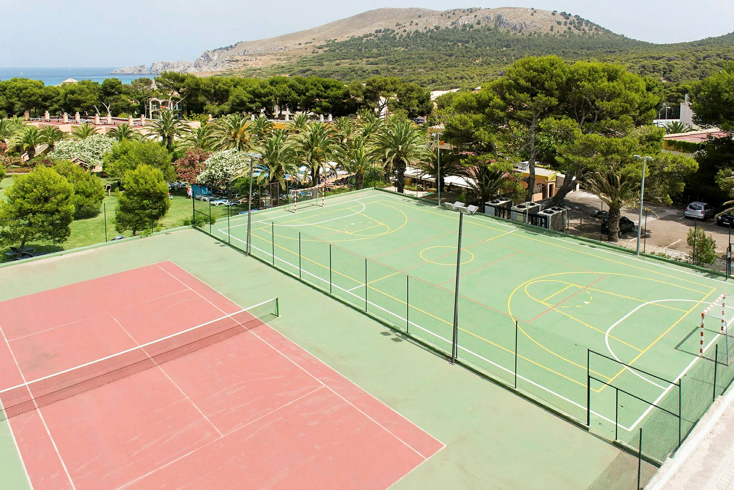 Billede af en tennisbane ved siden af en multifunktionel sportsbane omgivet af grønt. (AI-genereret tekst)