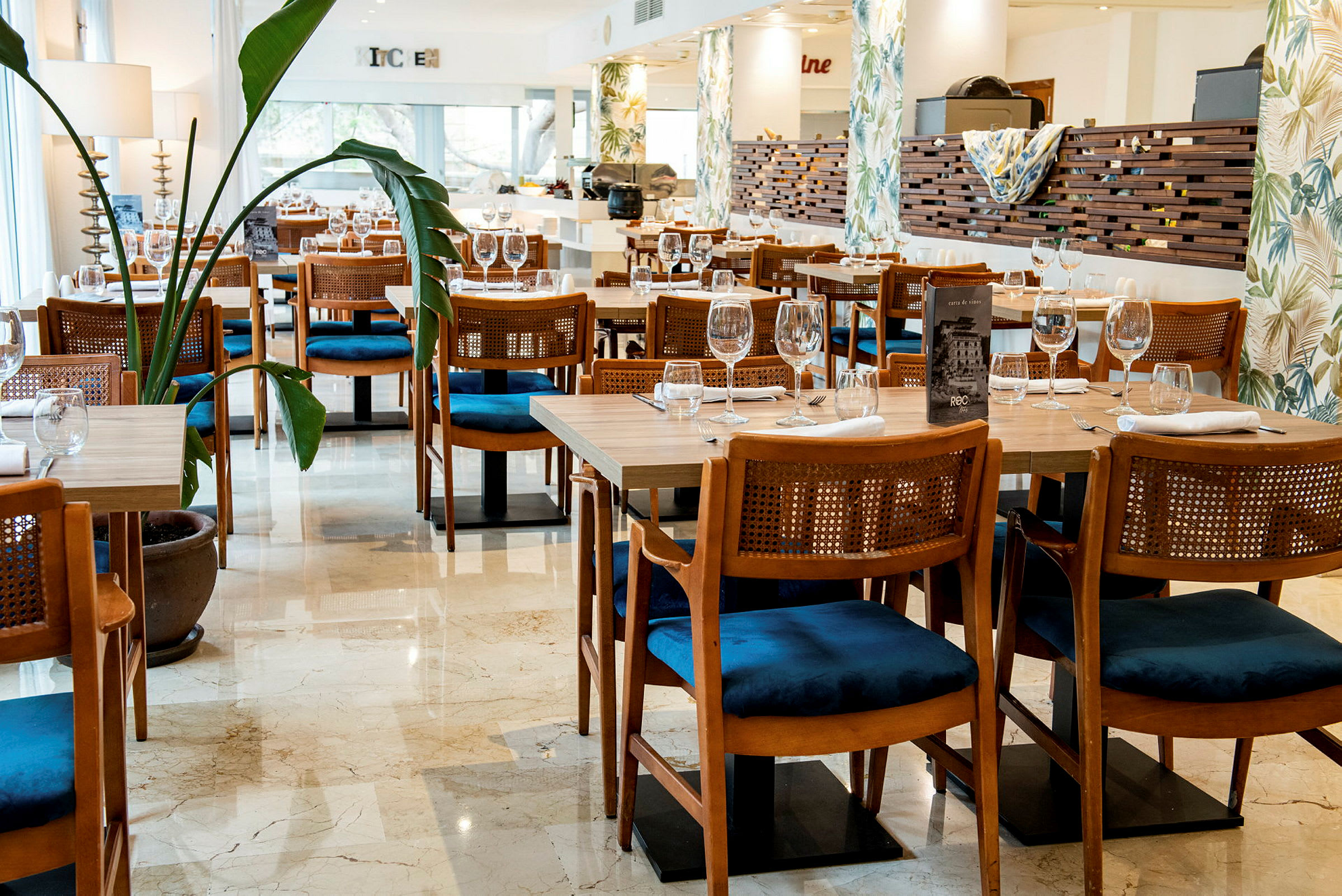 En restaurant med dækkede borde og stole samt planter i potter. (AI-genereret tekst)