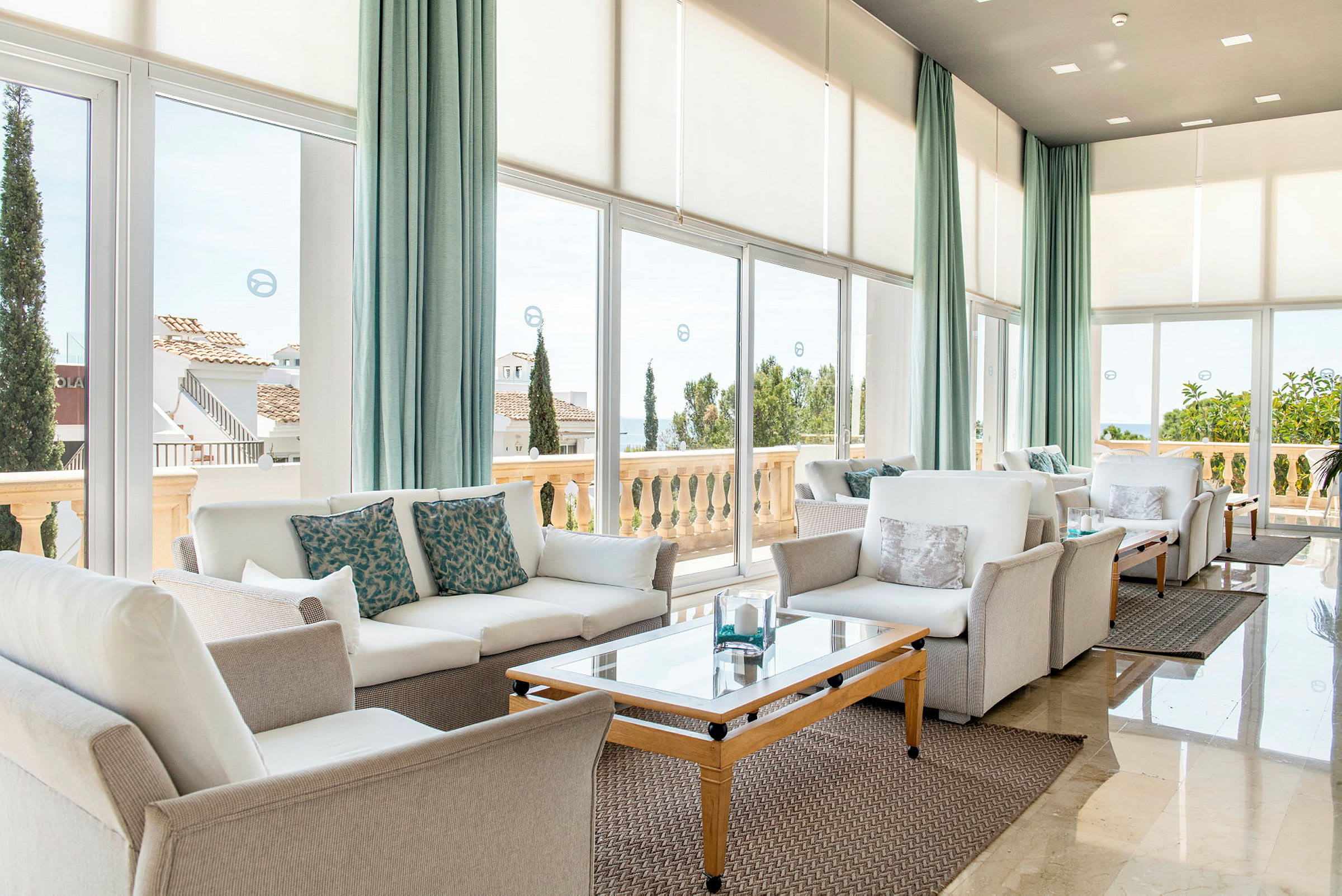 En lys lounge med moderne sofaer og store vinduer der vender ud mod en terrasse. (AI-genereret tekst)