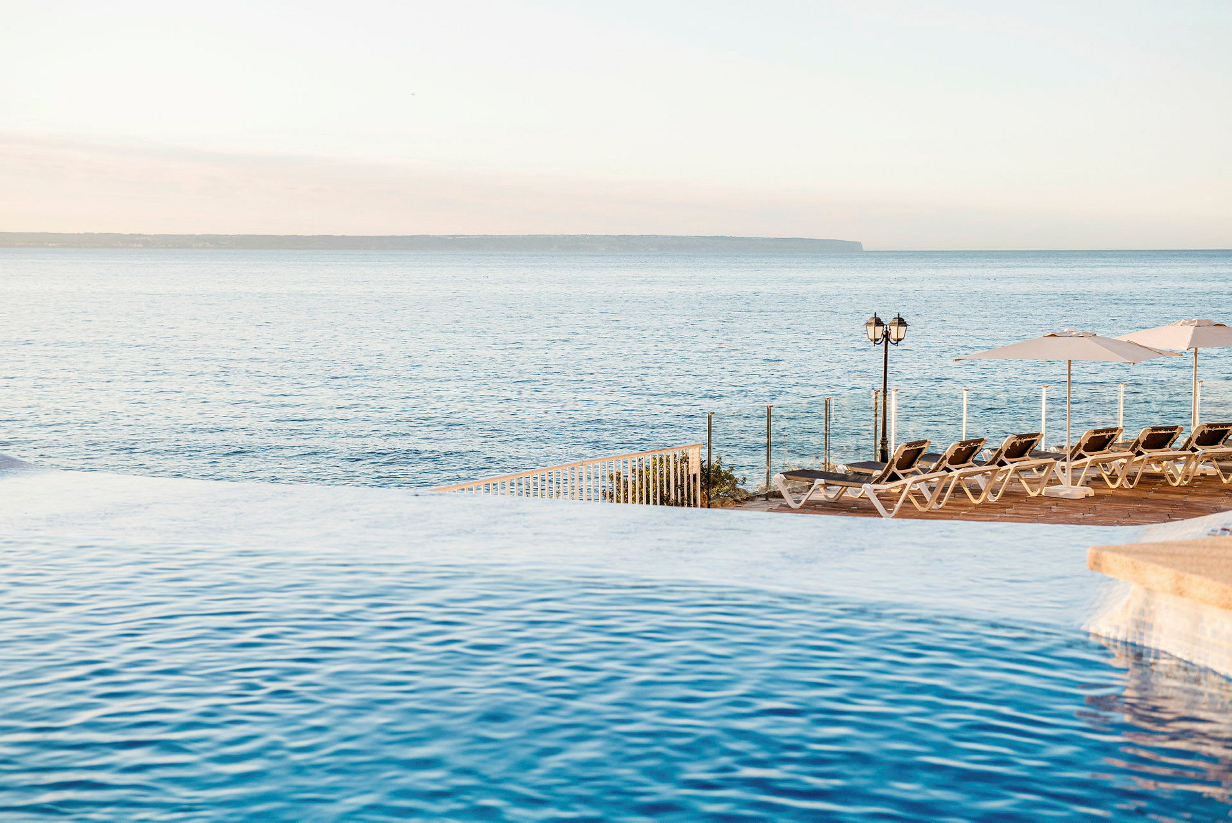 Pool med udsigt over havet og liggestole på terrassen. (AI-genereret tekst)
