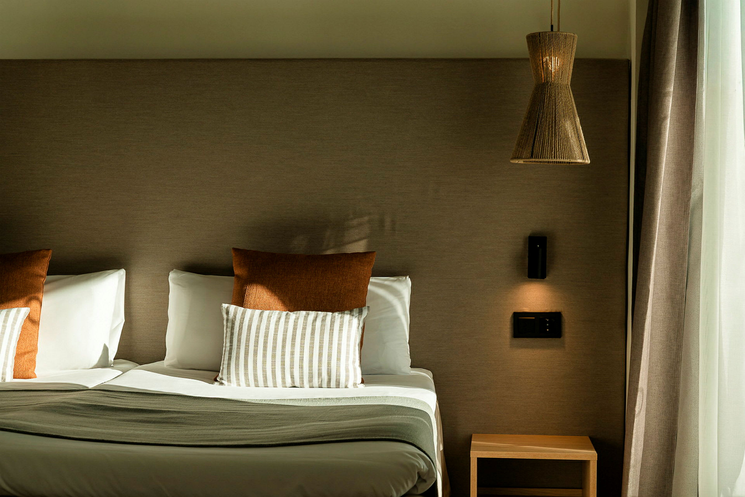 Hotelseng med to puder, et natbord og en væglampe. (AI-genereret tekst)