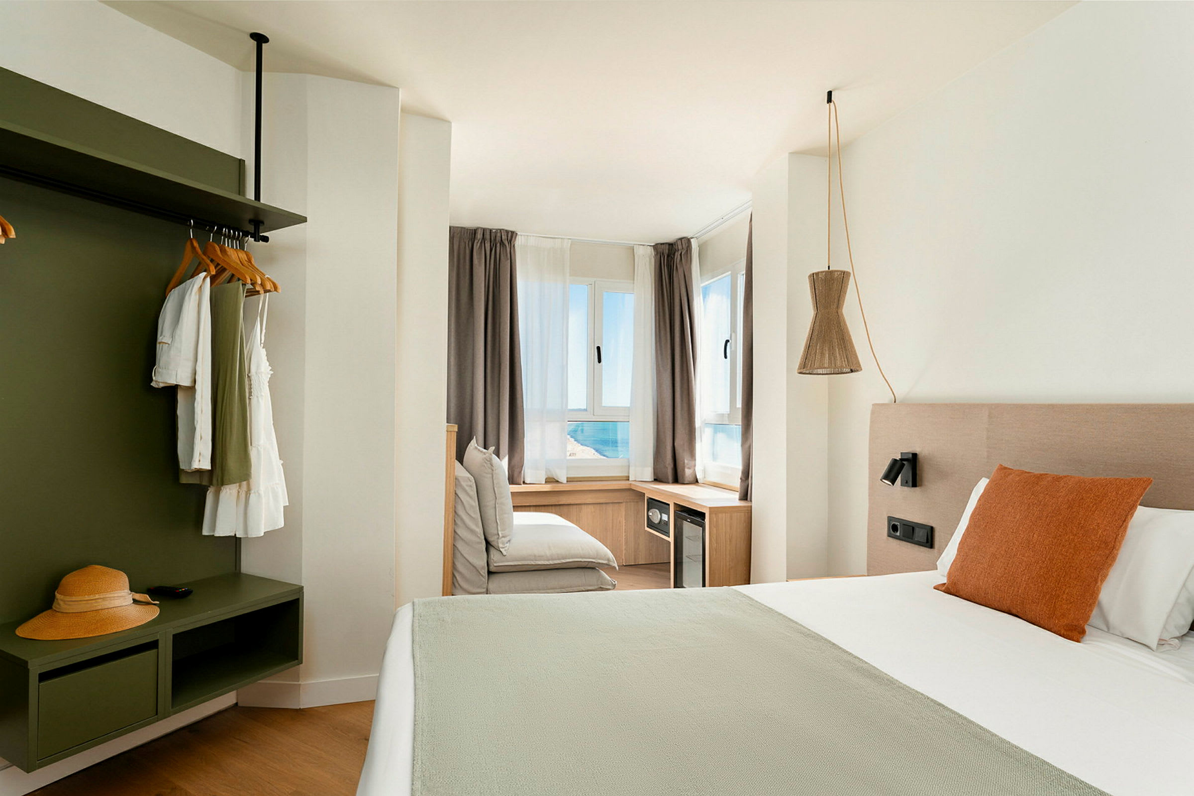 Et lyst og moderne hotelværelse med en stor seng og havudsigt gennem vinduerne. (AI-genereret tekst)