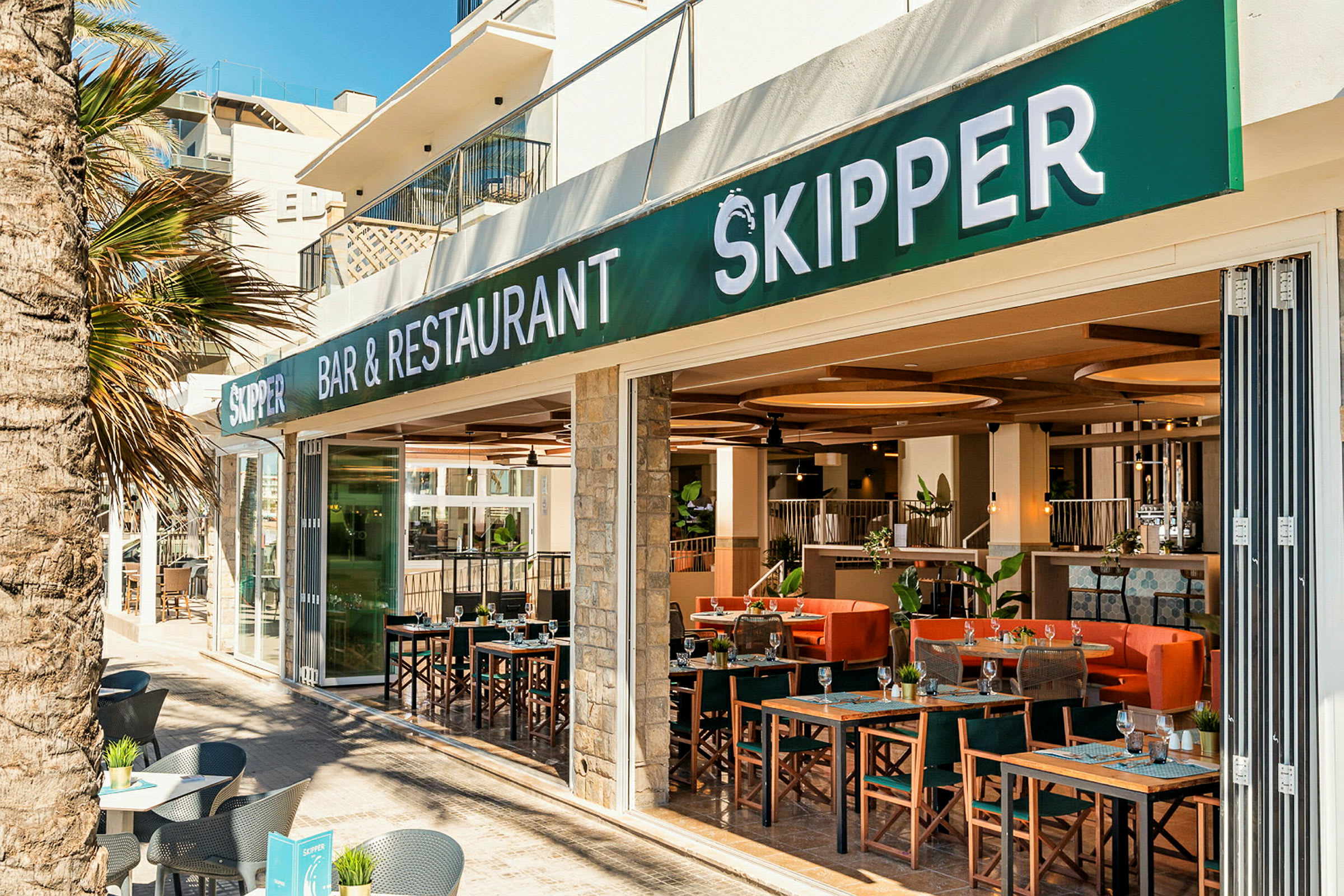 En restaurant og bar med navnet Skipper, udendørs siddepladser og interiør synligt. (AI-genereret tekst)
