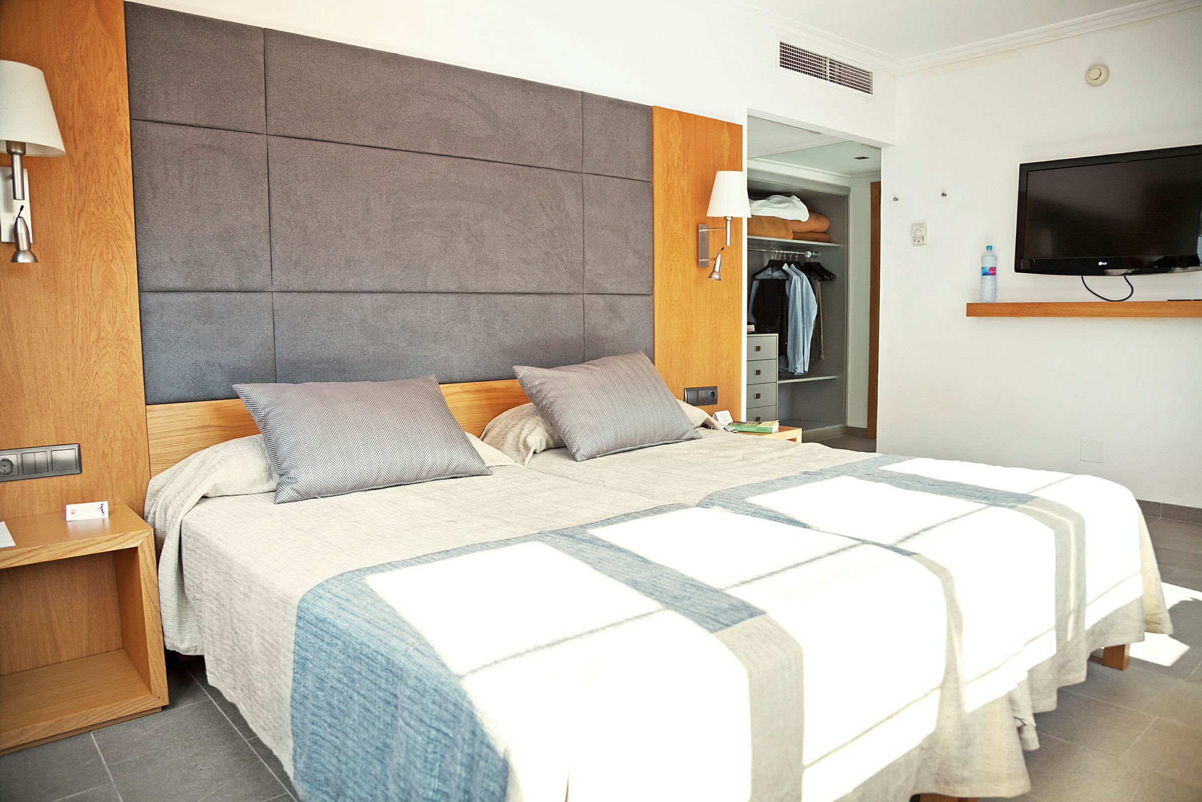 Billede der viser et moderne hotelværelse med en dobbeltseng, et garderobeskab og et vægmonteret TV. (AI-genereret tekst)