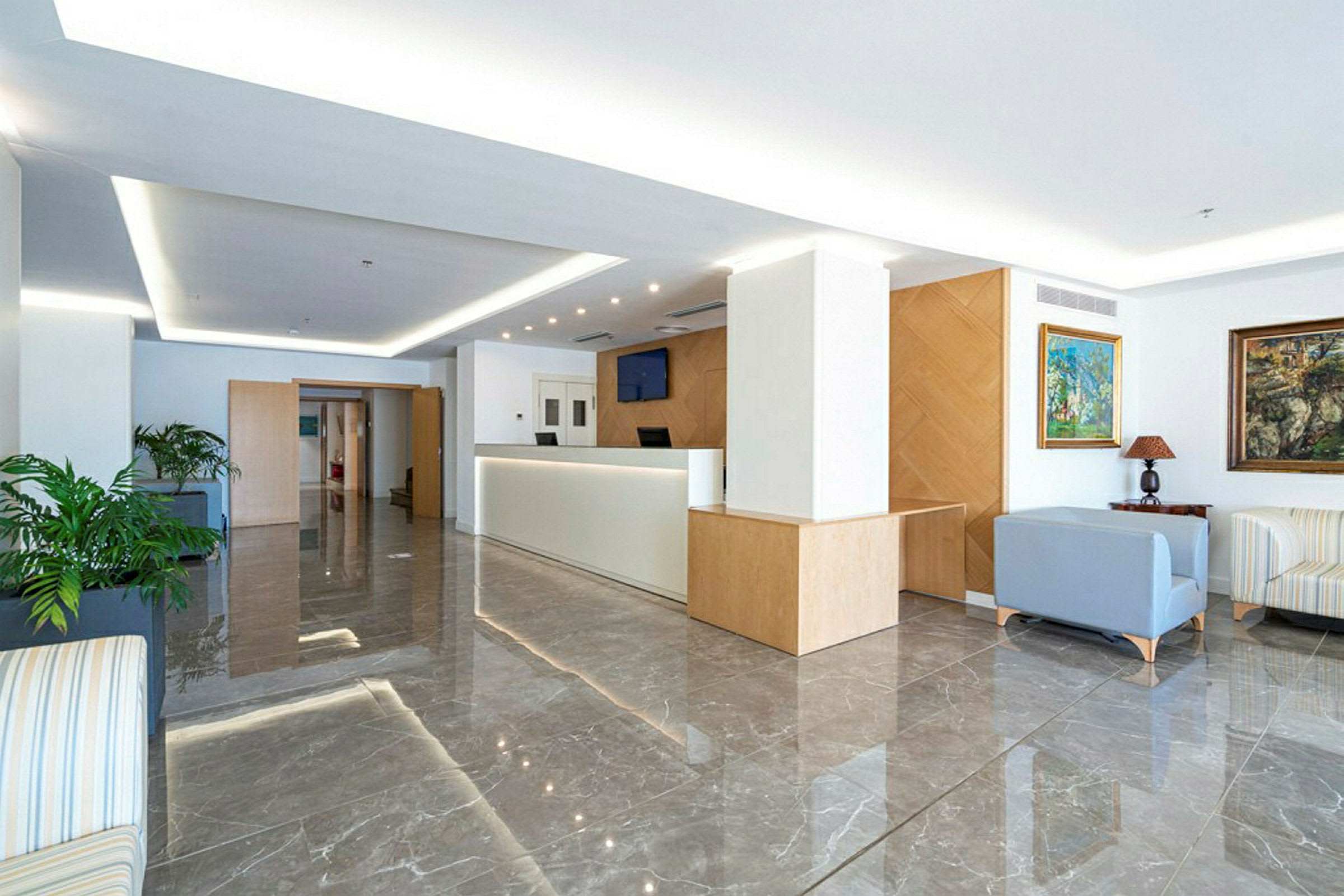 Et moderne og lyst hotelområde med en reception og siddegruppe. (AI-genereret tekst)