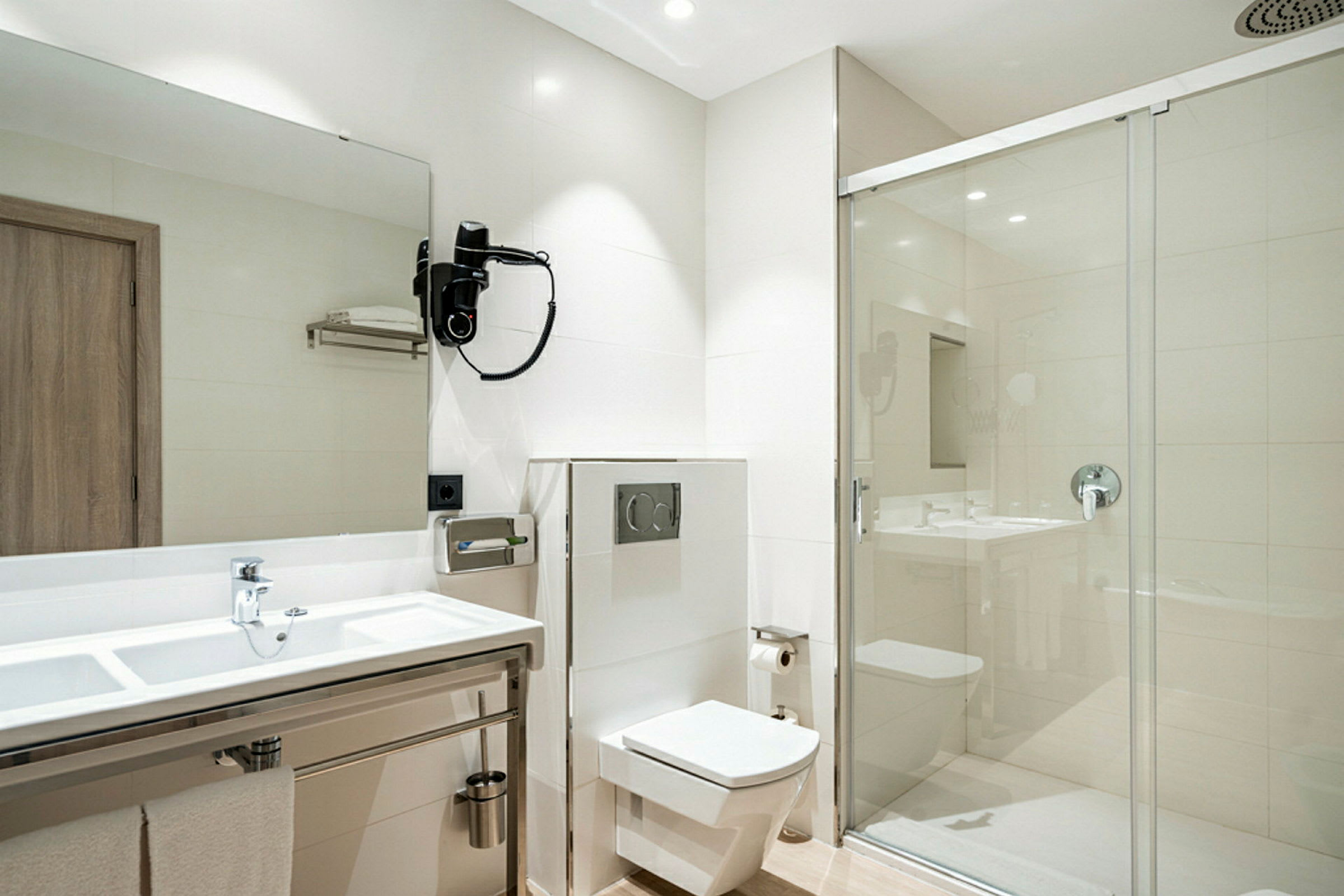Et moderne badeværelse med hvidt interiør, håndvask, toilet og brusebad med glasdør. (AI-genereret tekst)