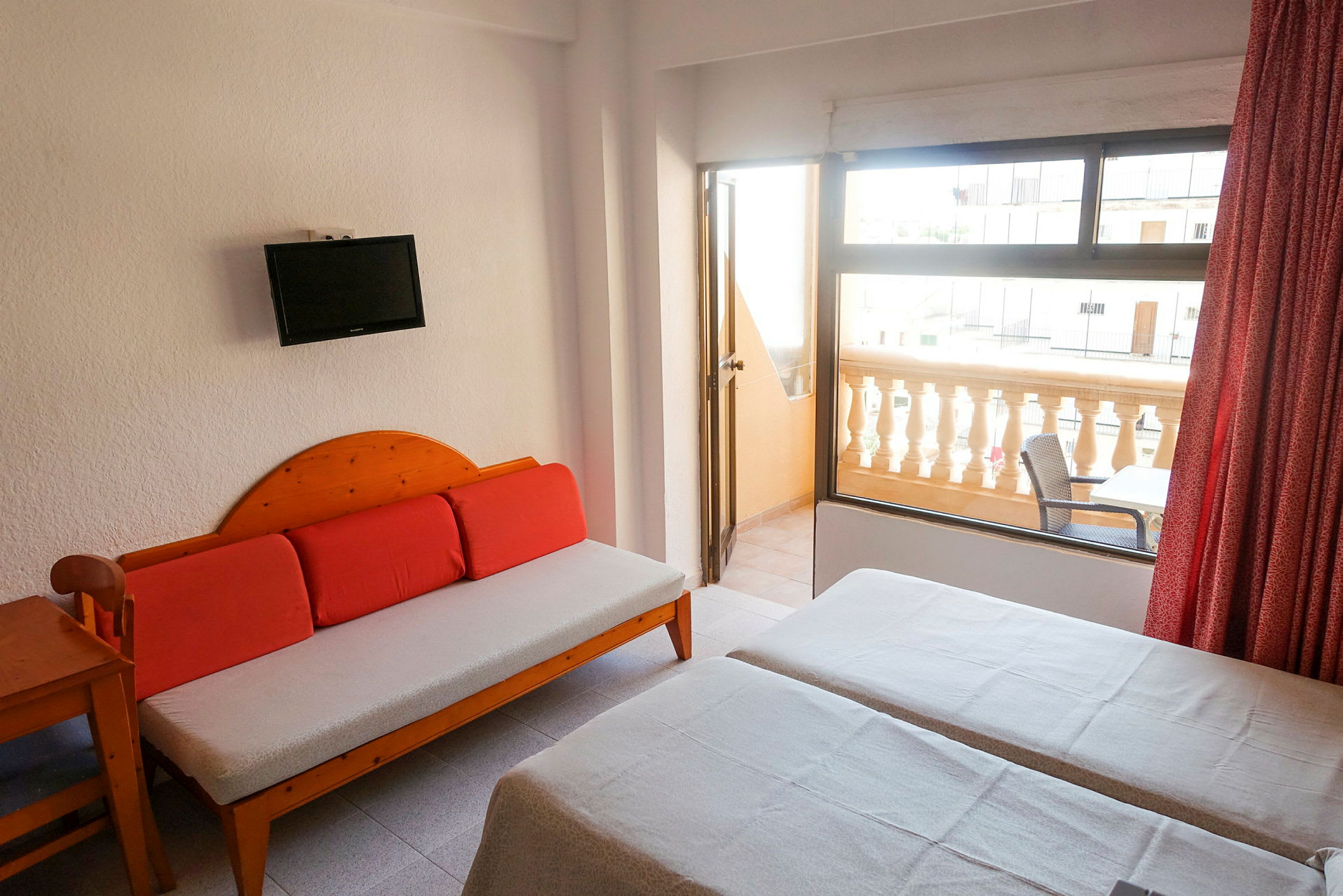 Et hotelværelse med to enkeltsenge, en sofa og en balkon med siddepladser. (AI-genereret tekst)