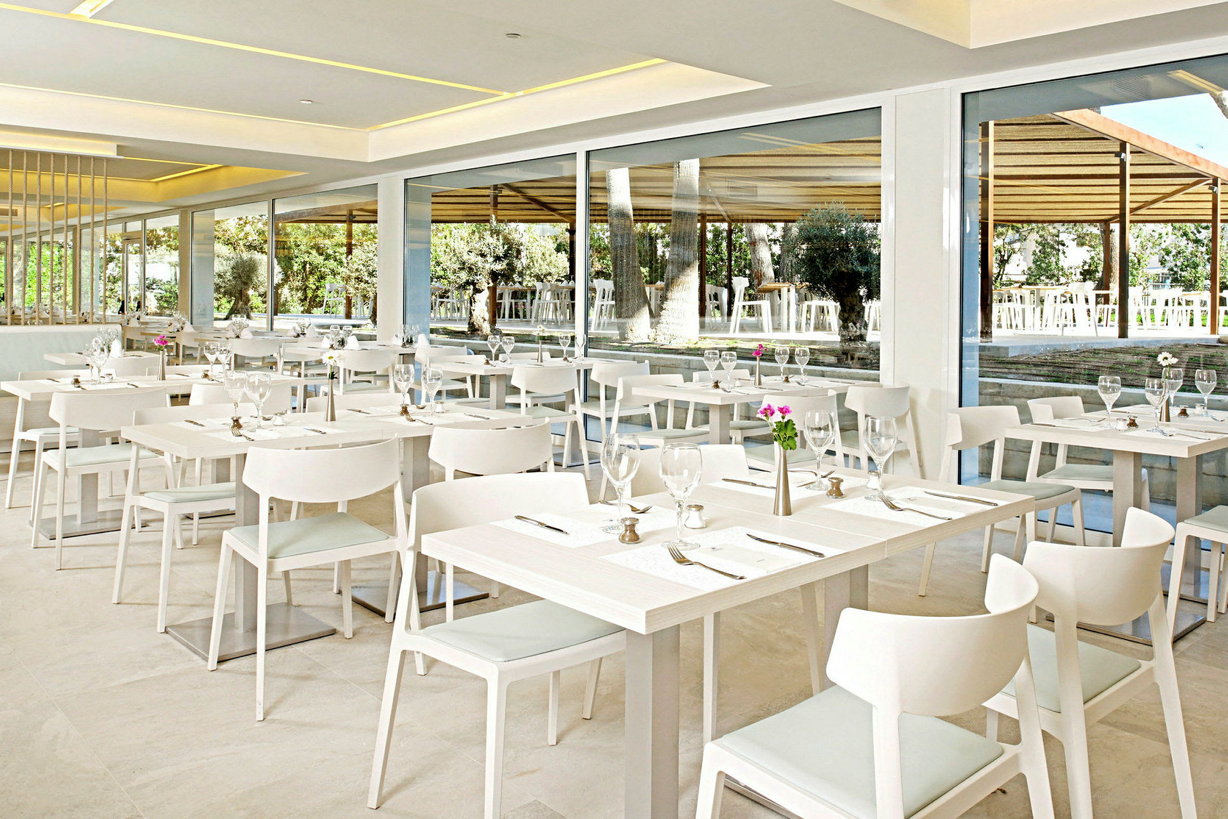 En moderne restaurant med hvide møbler og bordopdækning. (AI-genereret tekst)