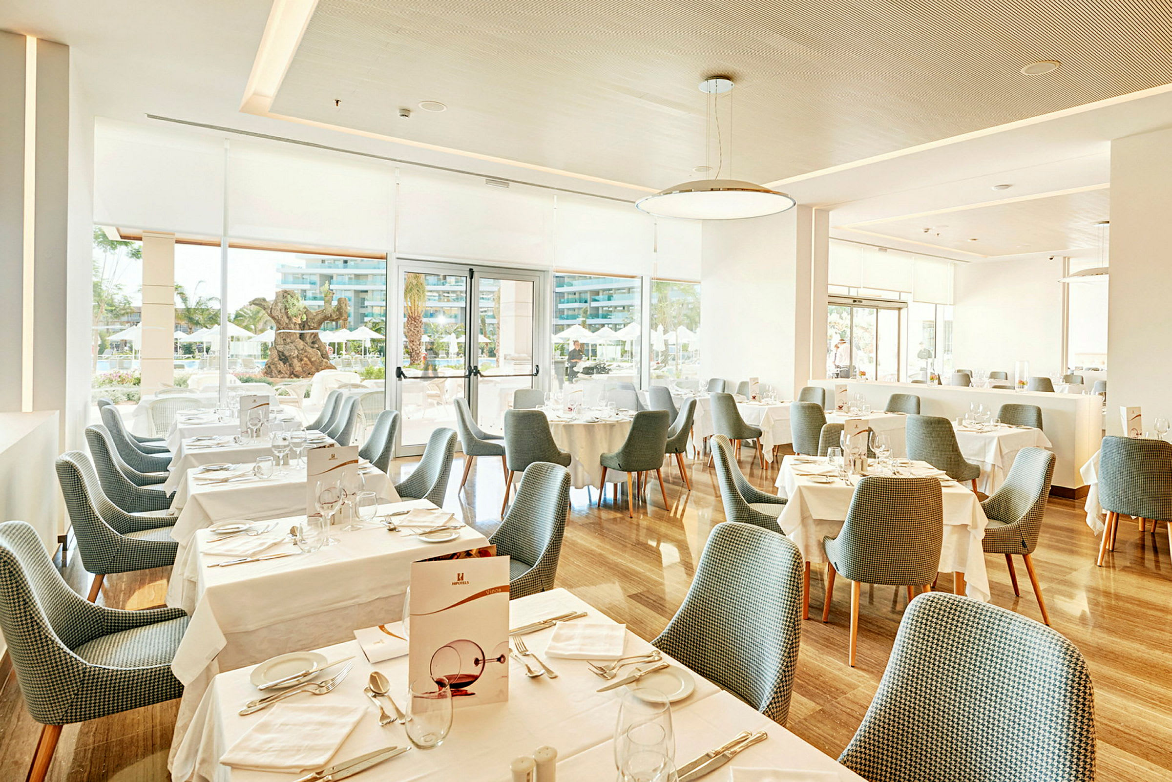 En lys restaurant med dækkede borde og blå stole. (AI-genereret tekst)
