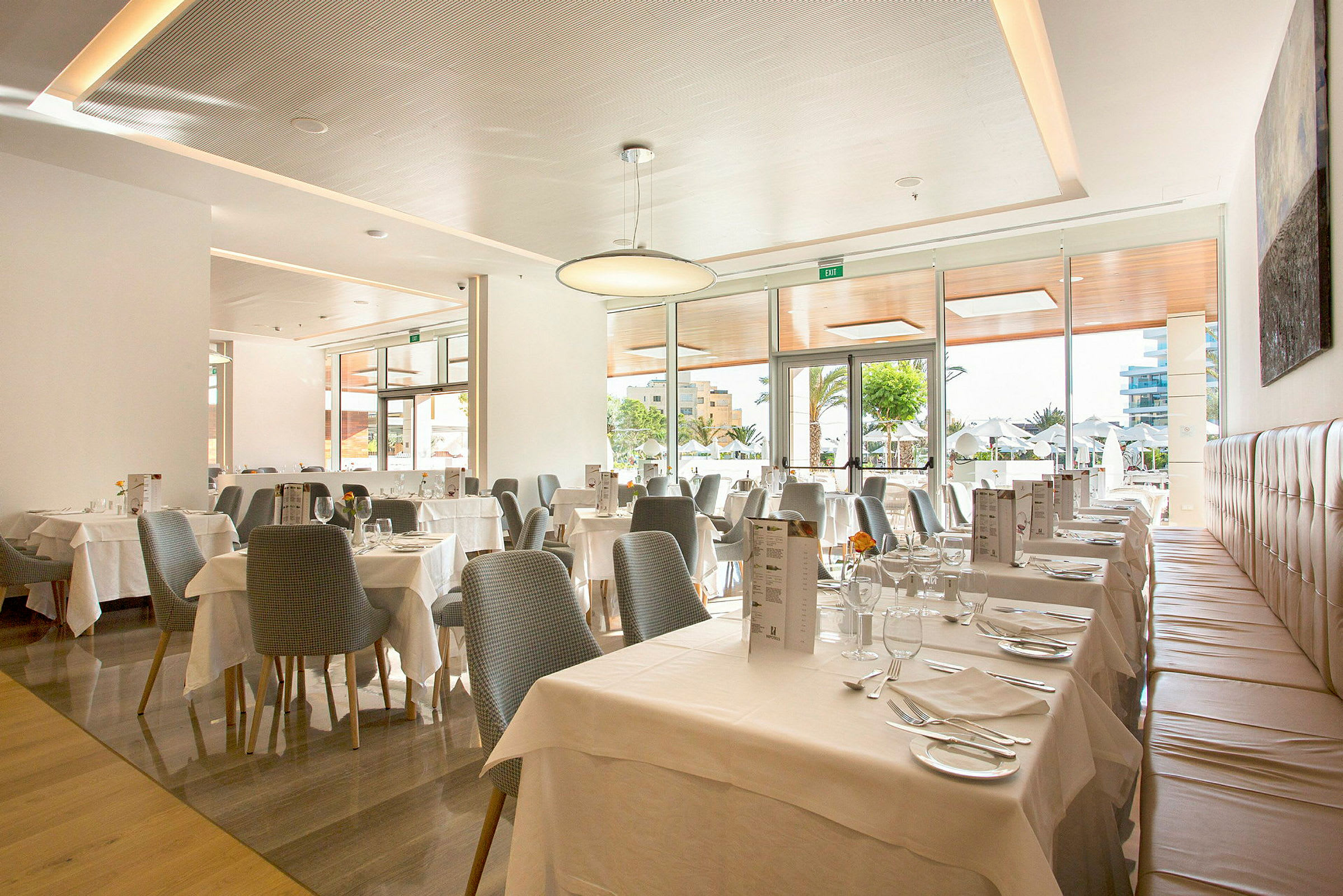 En lys og moderne restaurant med dækkede borde og store vinduer. (AI-genereret tekst)