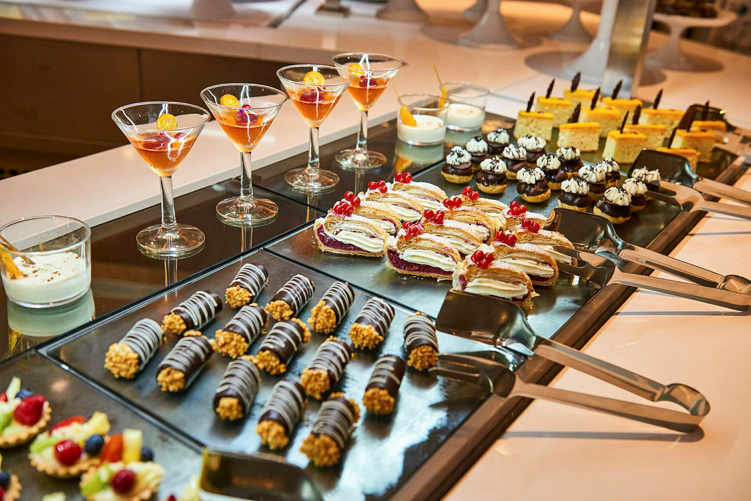 Et udvalg af desserter og dessertglas på en buffet. (AI-genereret tekst)
