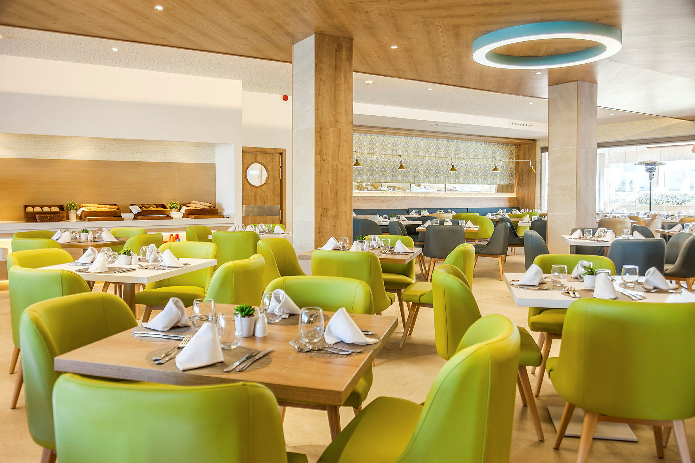 Interiør af en restaurant med grønne stole og dækkede borde. (AI-genereret tekst)