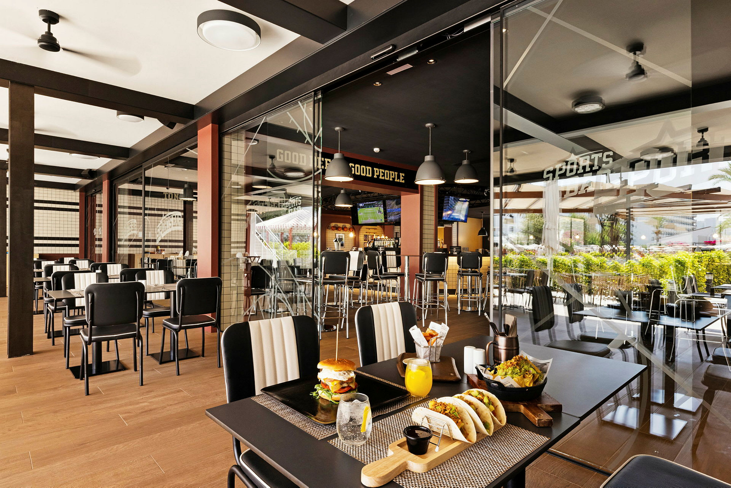 En moderne restaurant med glasvæg, bordopstillinger og synlige madretter. (AI-genereret tekst)