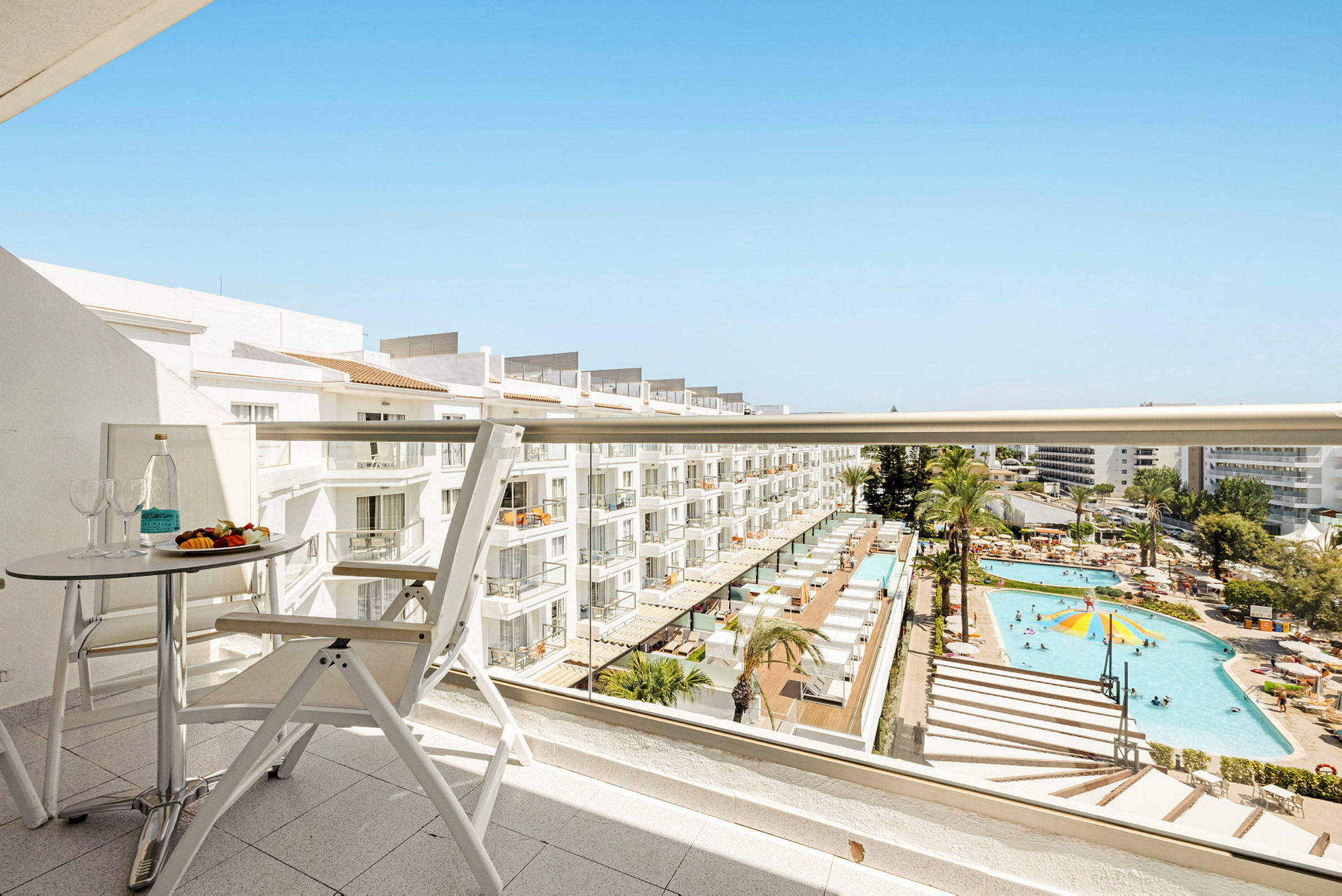 Udsigt fra en altan over hotelområde med pool og liggestole. (AI-genereret tekst)