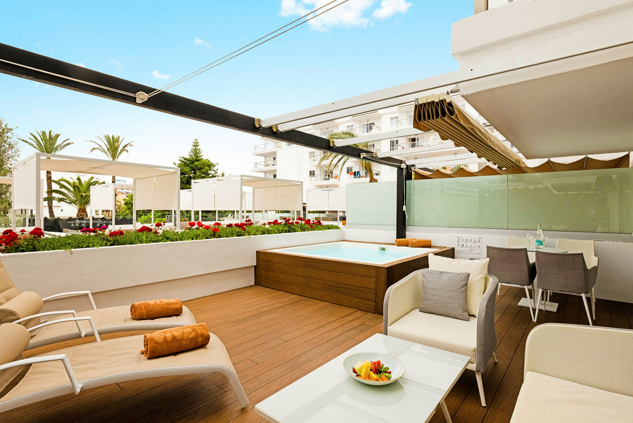 Billede af en terrasse med liggestole, spisebord og en lille pool, omgivet af blomster og skyggefulde tag. (AI-genereret tekst)