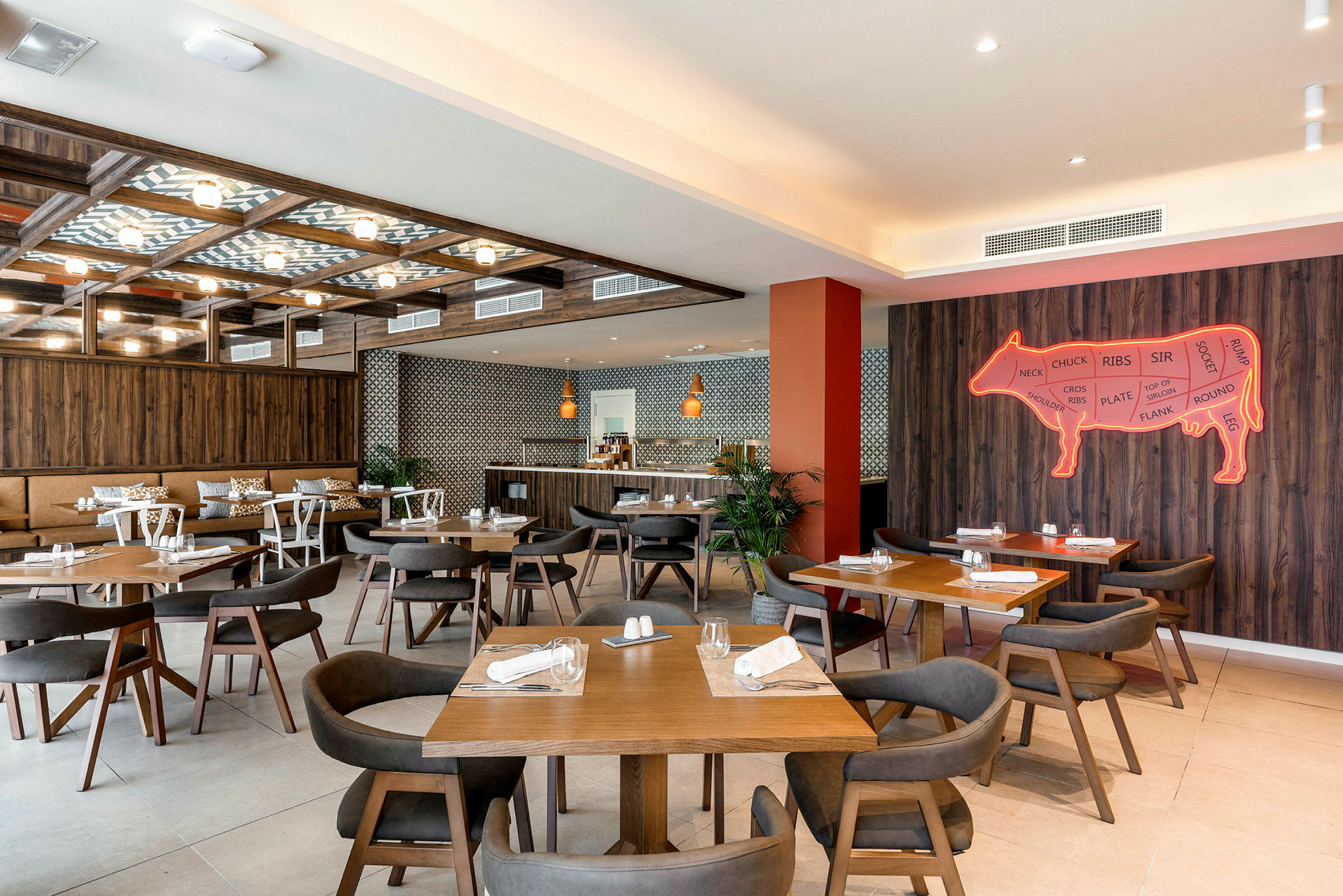 Interiør af en restaurant med flere træborde og stole, vægdekoration i form af et neonskilt af en ko. (AI-genereret tekst)