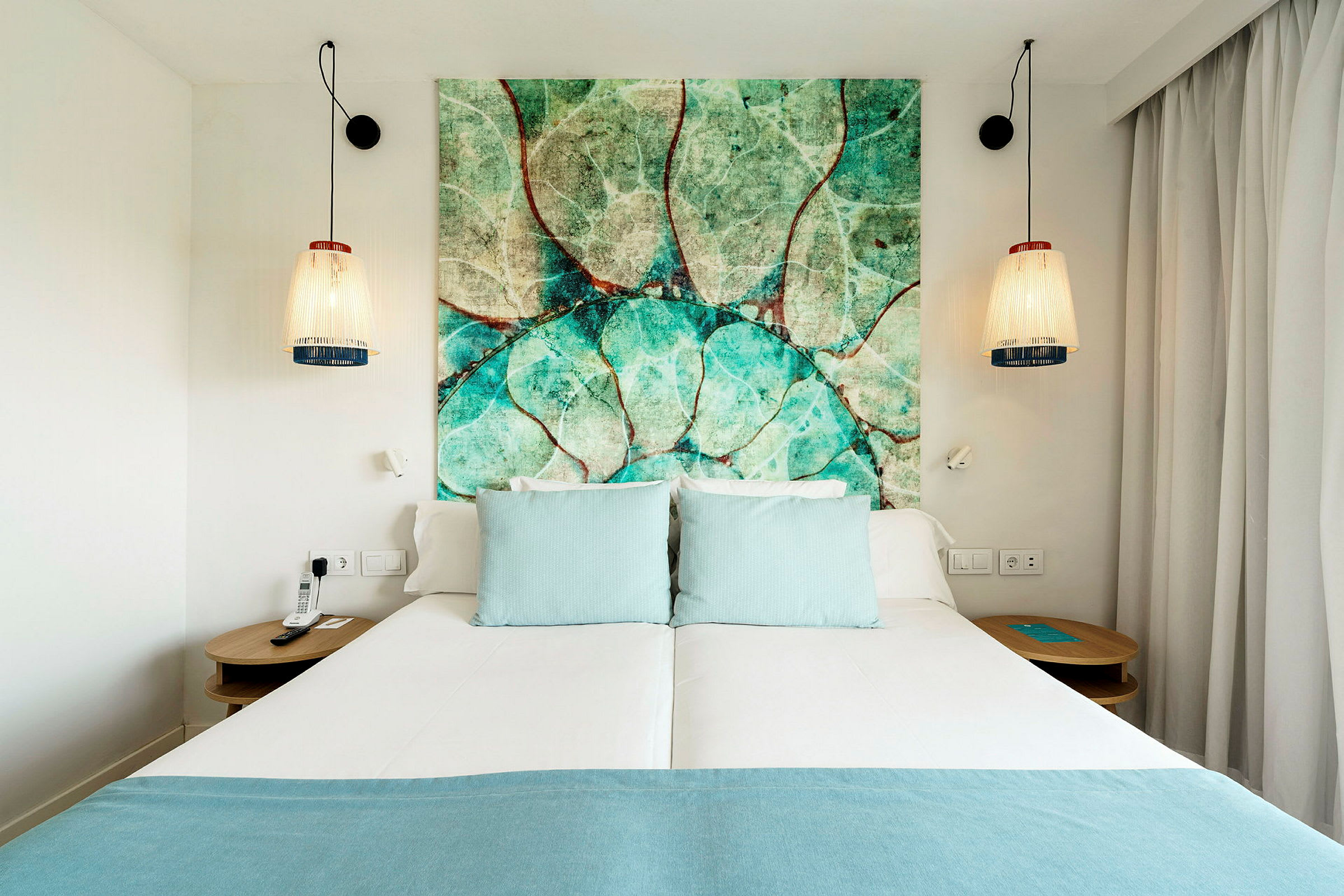 Hotelseng med turkise puder og en sengegavl med naturmotiv. (AI-genereret tekst)