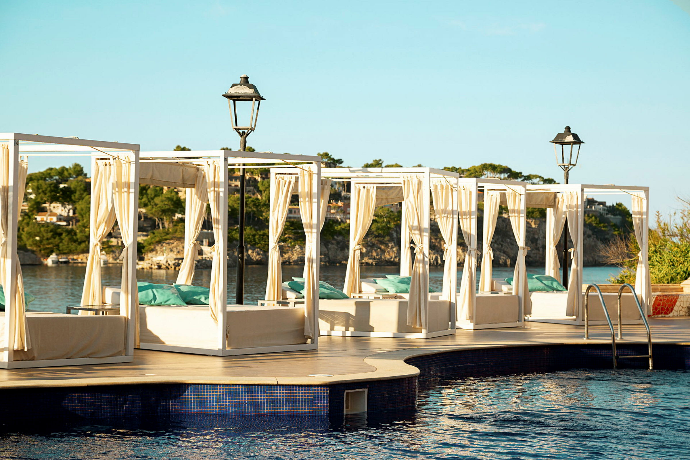 Solstole med gardiner ved en pool med udsigt over havet. (AI-genereret tekst)