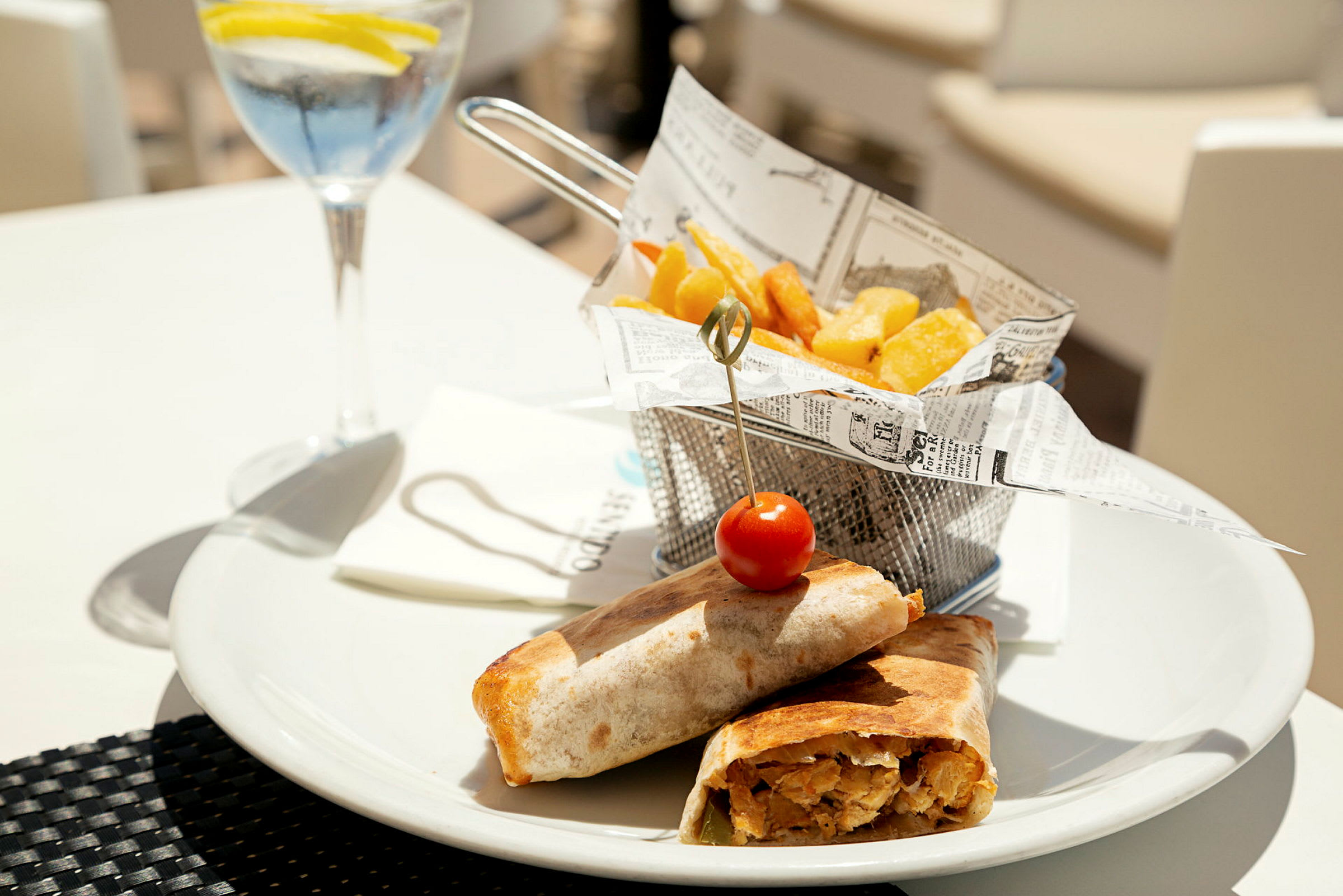 Et måltid med wraps, pomfritter og en glasdrik. (AI-genereret tekst)