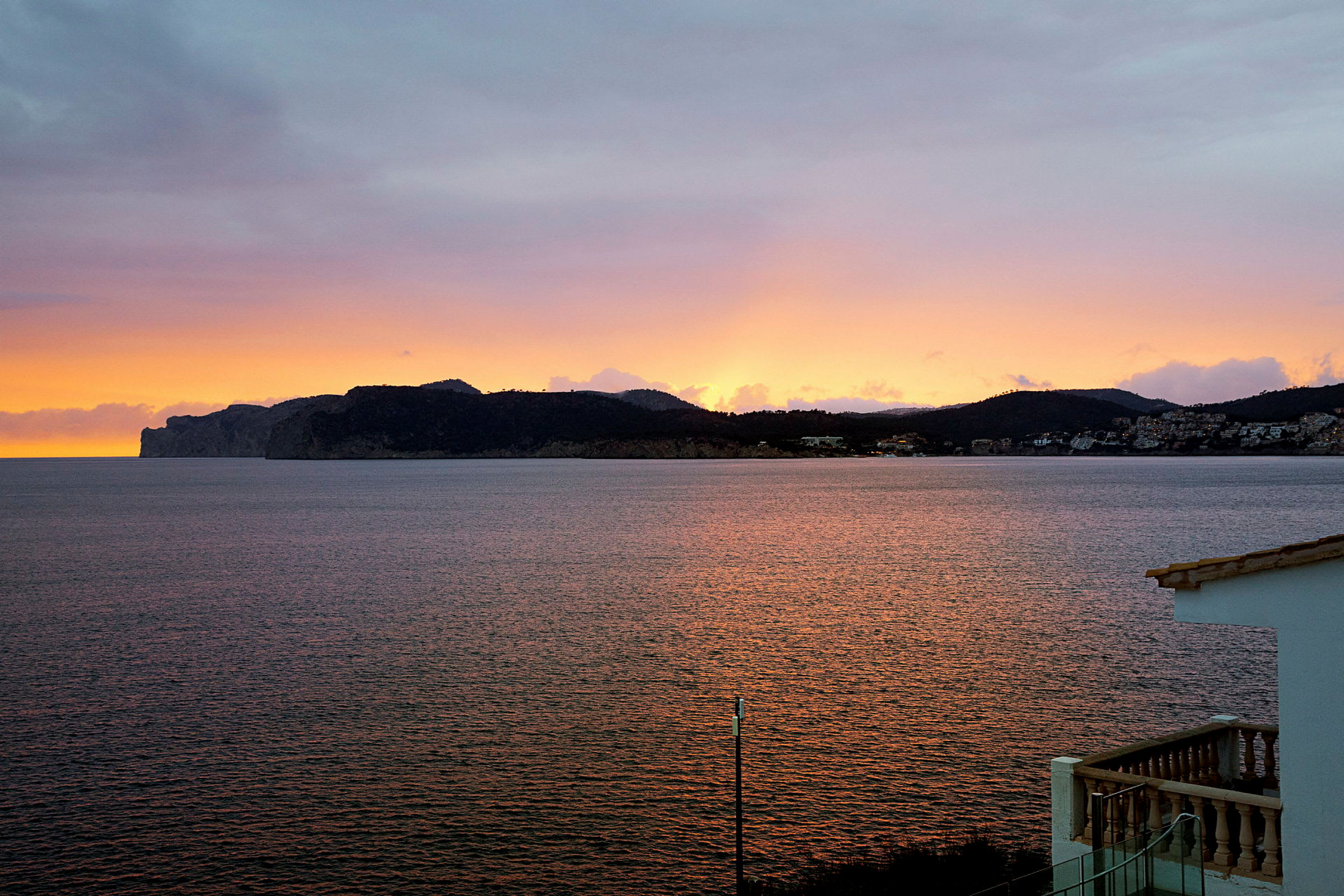 Solnedgang over en bjergrig kystlinje ved havet. (AI-genereret tekst)