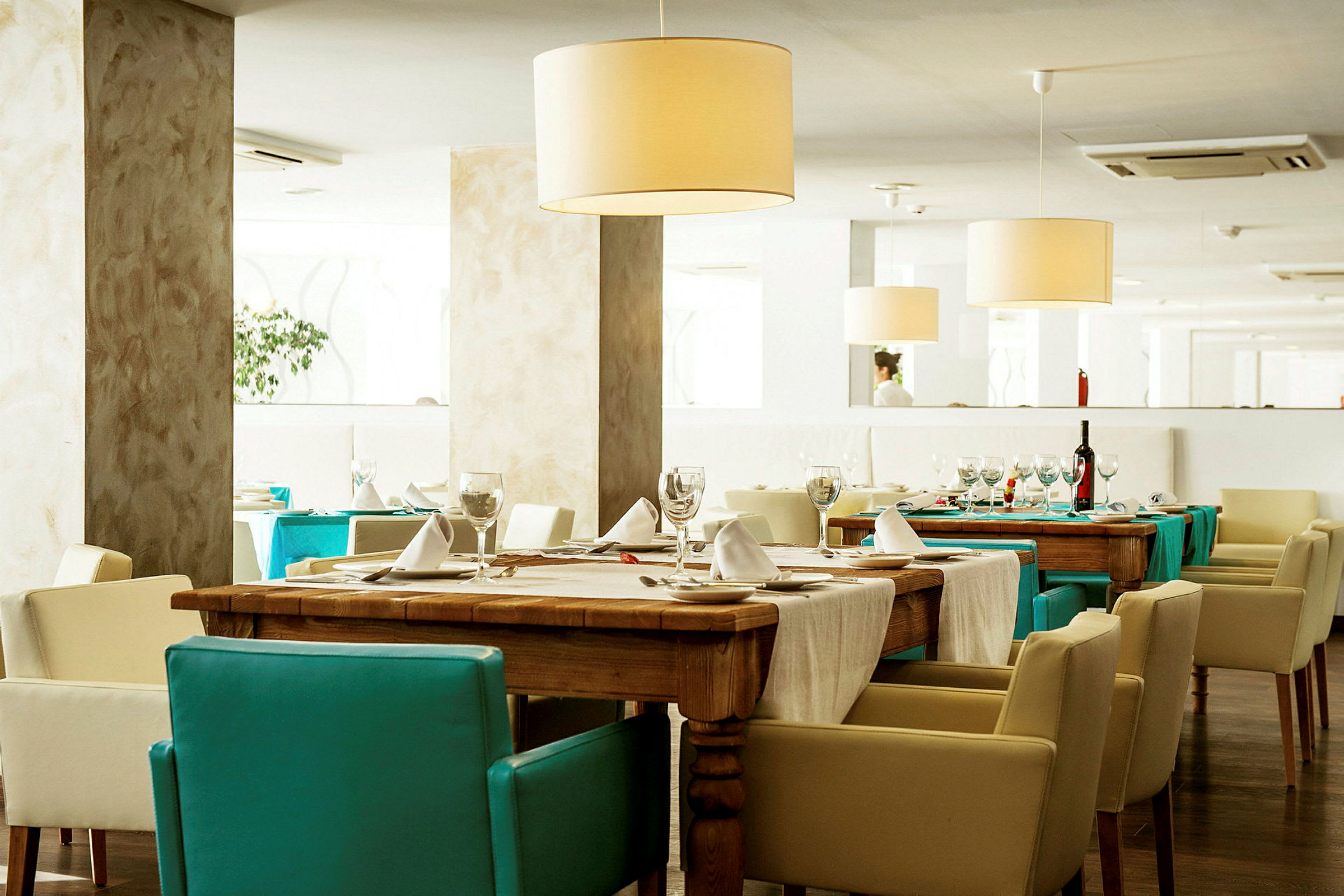 Et elegant restaurantinteriør med dækkede borde og lyse stole. (AI-genereret tekst)