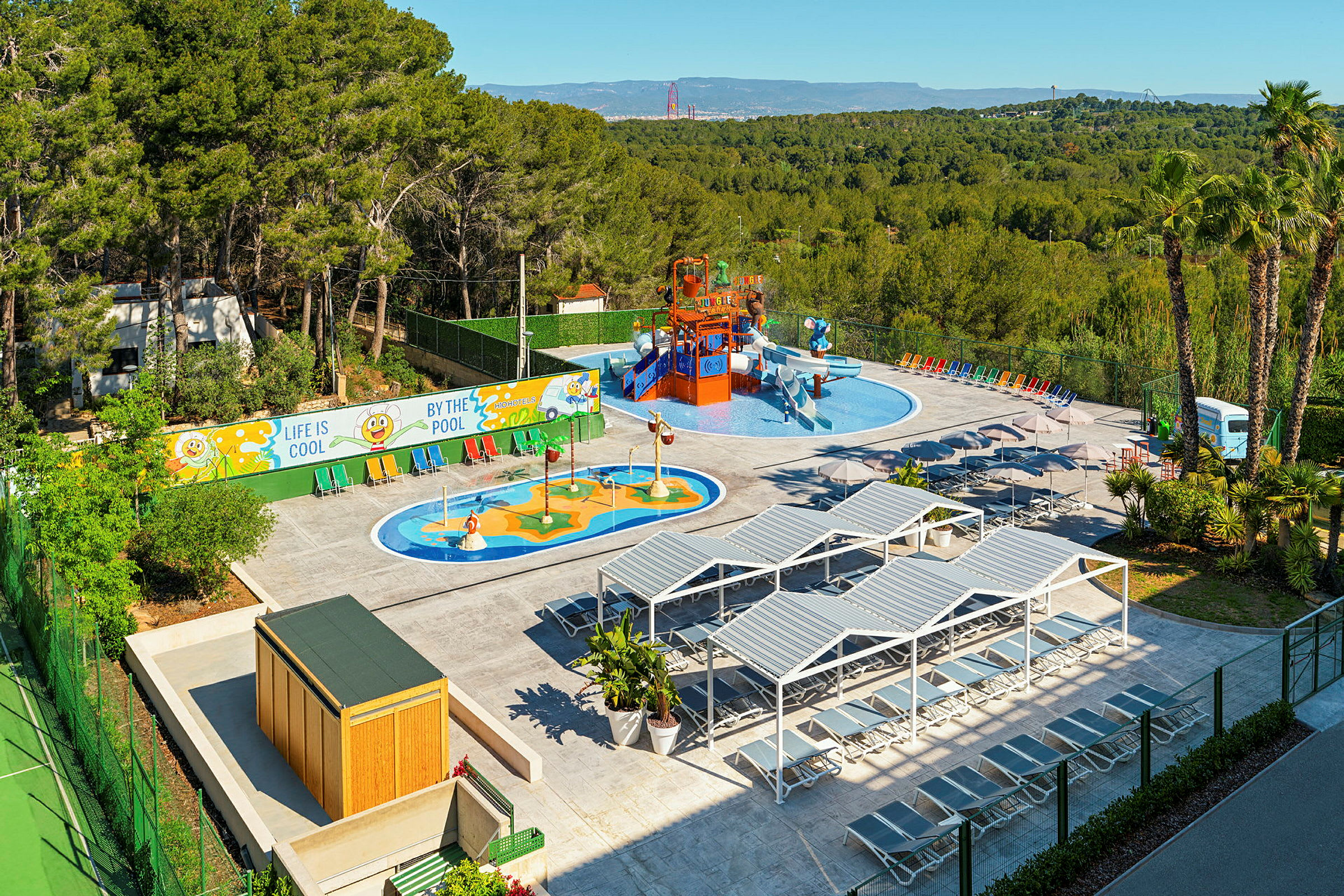 Udendørs vandlegeplads med små pools og vandrutsjebaner omgivet af grønt og liggestole. (AI-genereret tekst)