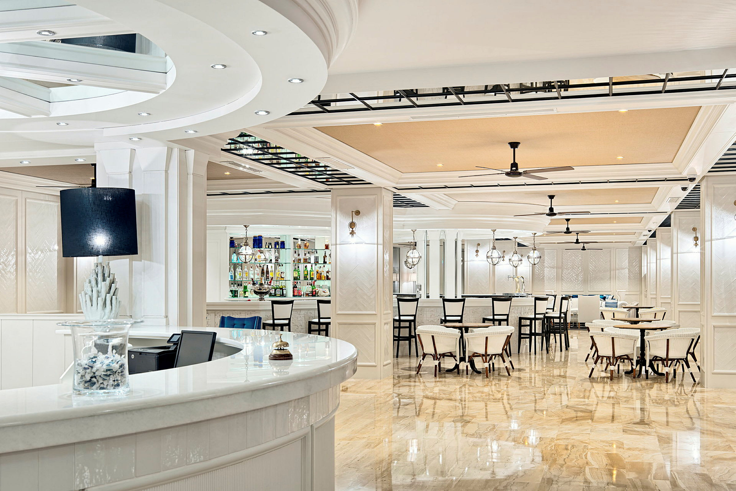 Billedet viser en lys og elegant bar og restaurantmiljø med hvidt interiør og spejlblanke gulve. (AI-genereret tekst)