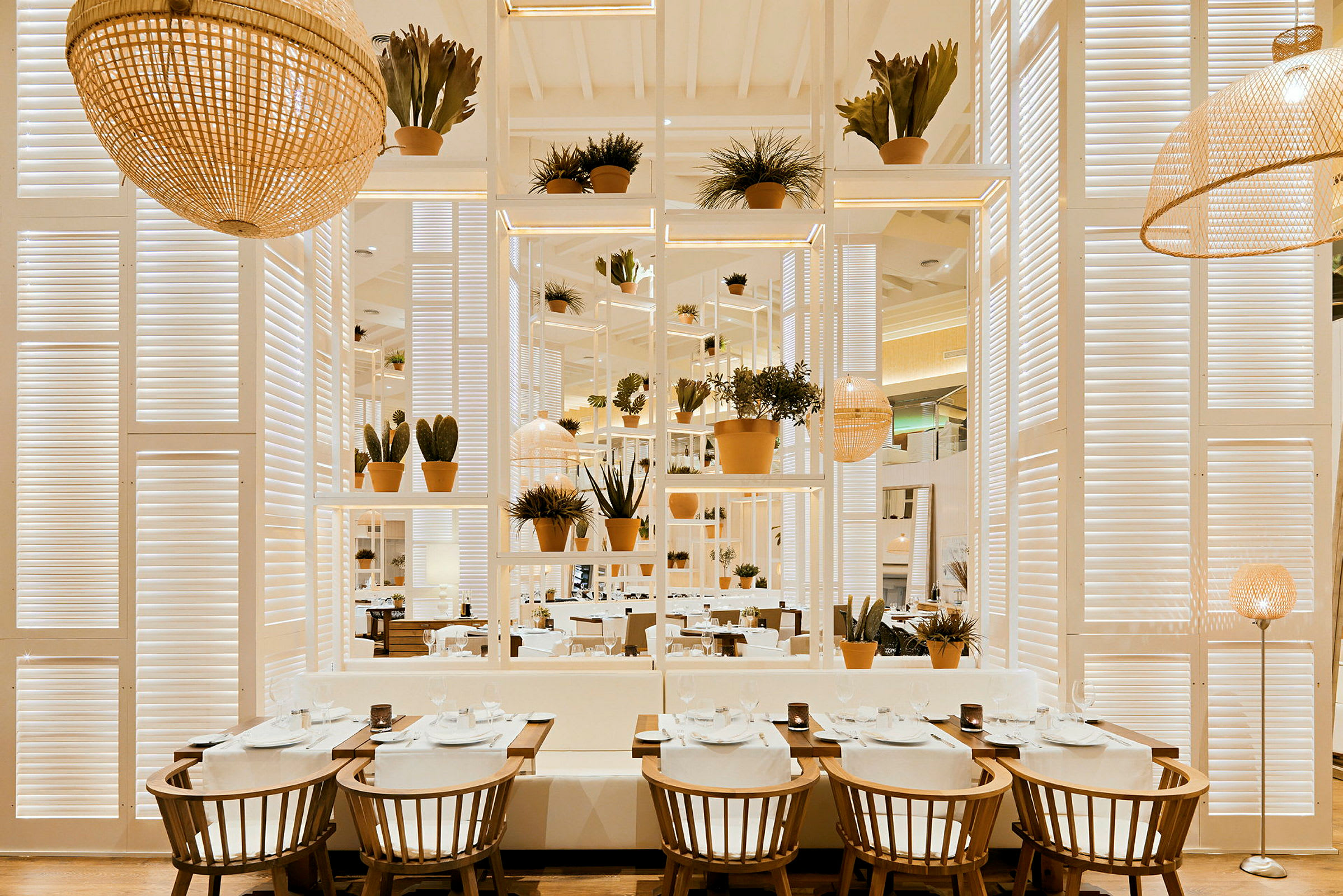Interiør af en restaurant med borde, stole og planter i et lyst og moderne design. (AI-genereret tekst)