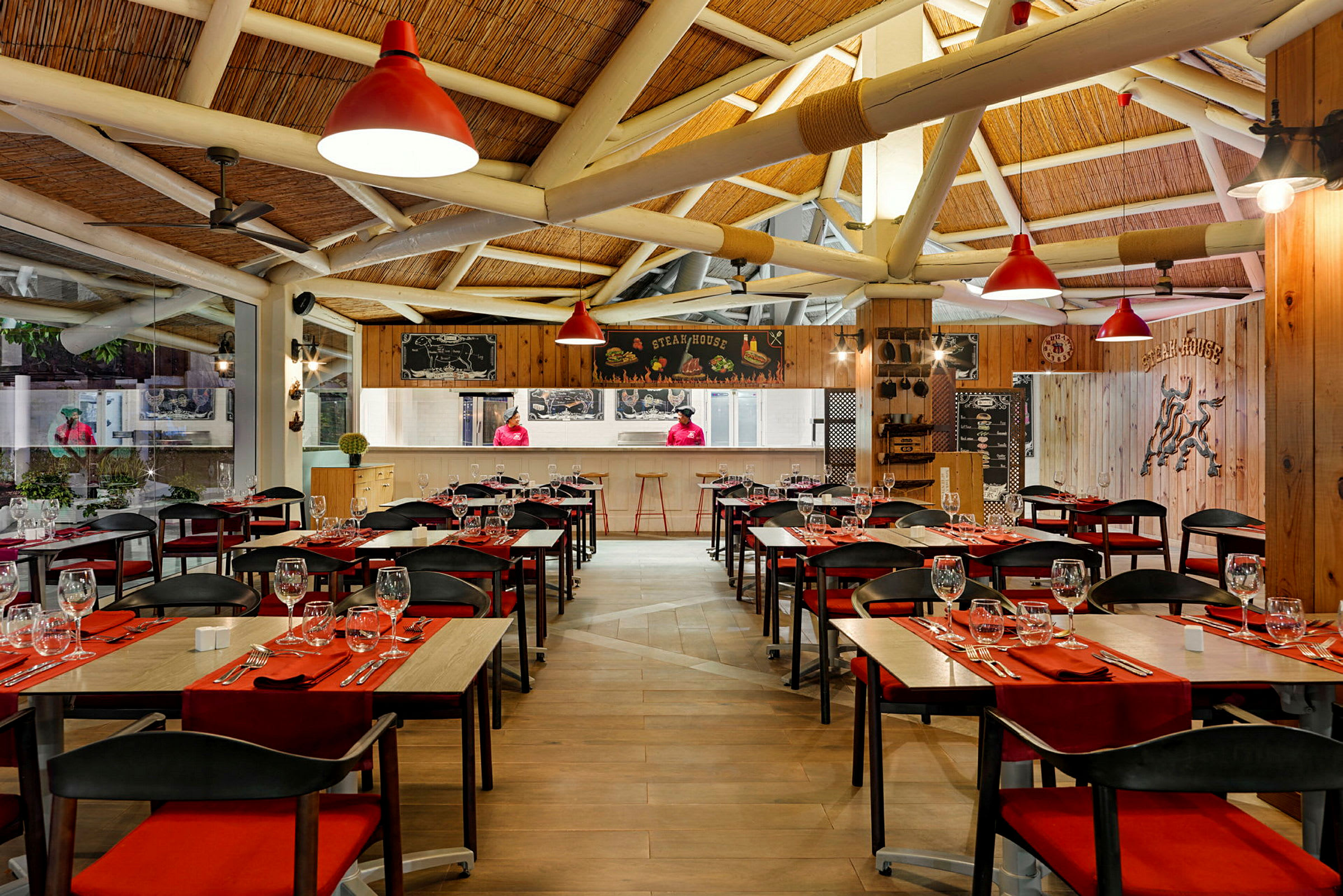 En indendørs restaurant med siddepladser, rød dekoration og synlige træbjælker i loftet. (AI-genereret tekst)