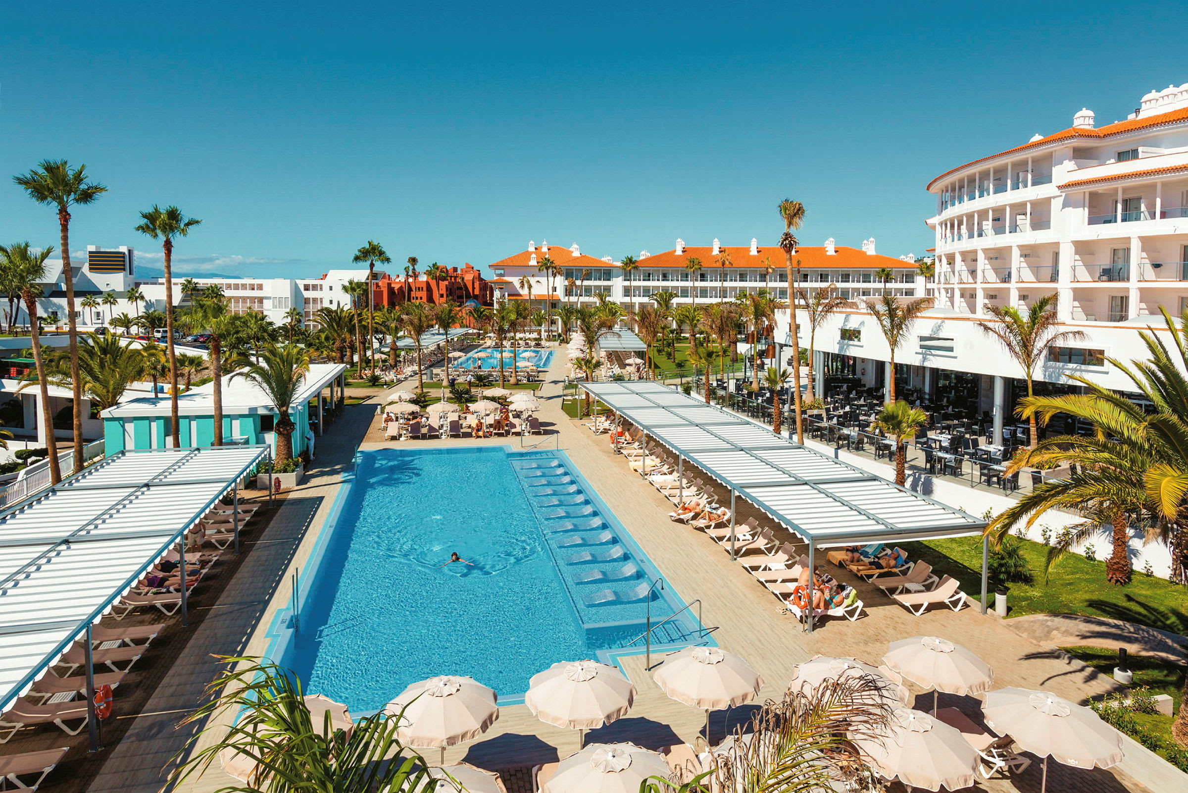 Udendørs pool ved hotelområde med liggestole og palmer. (AI-genereret tekst)