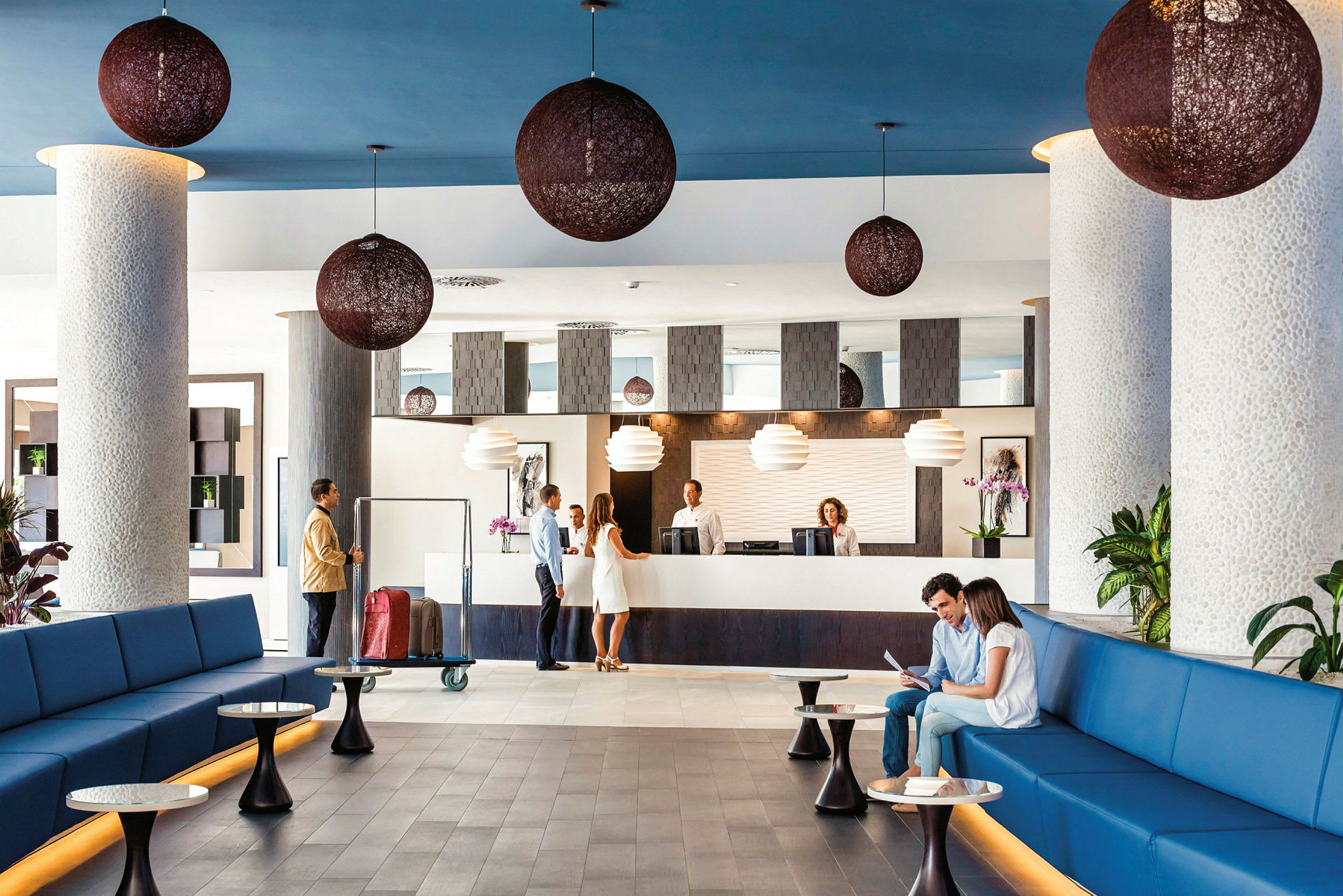 Lys hotellets lobby med siddeområder, reception og dekorativ belysning. (AI-genereret tekst)