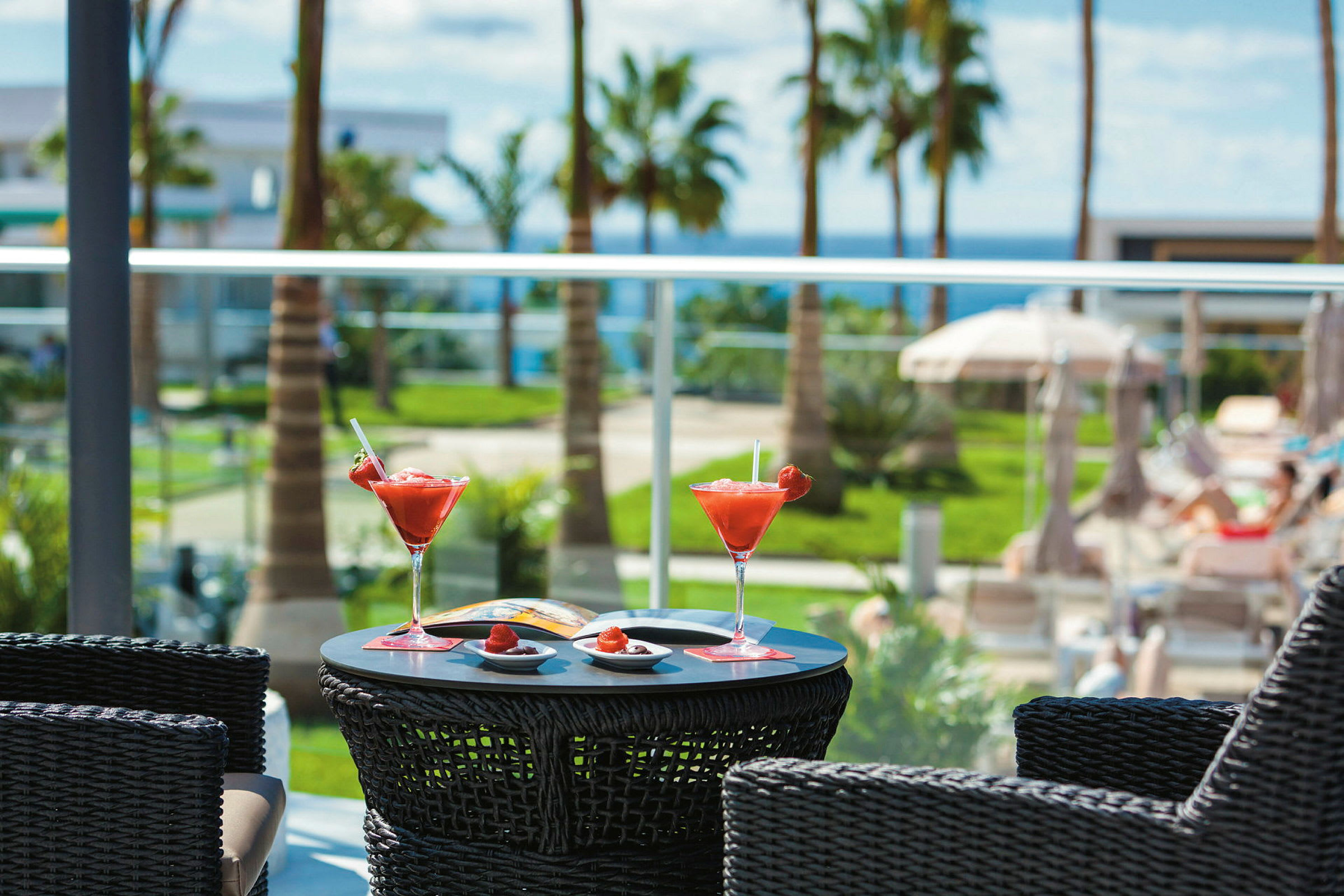 To glas med røde drinks står på et bord ved en solrig resort. (AI-genereret tekst)
