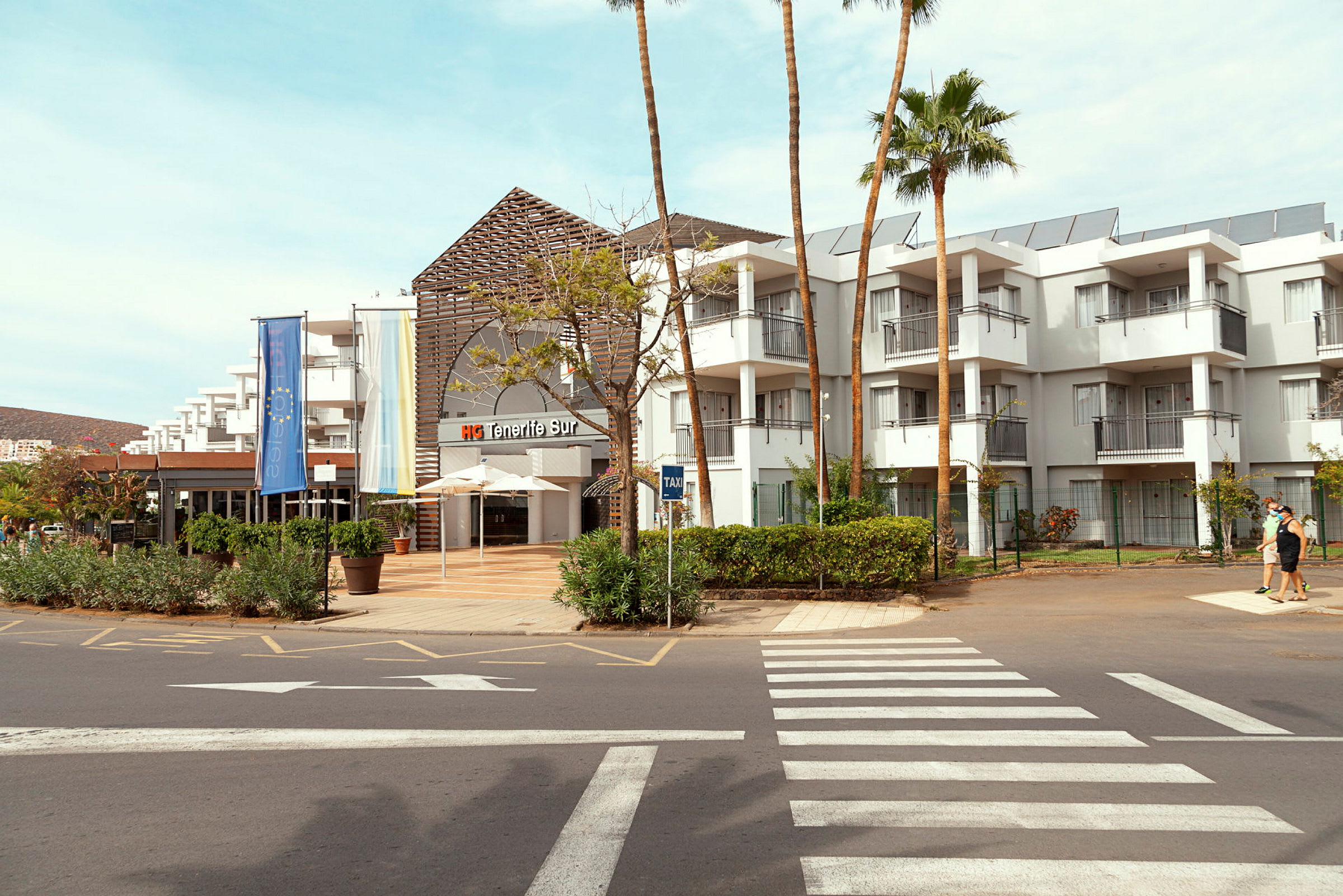 Hotelbygning med udsmykket indgangsområde og omkringliggende grønne områder. (AI-genereret tekst)