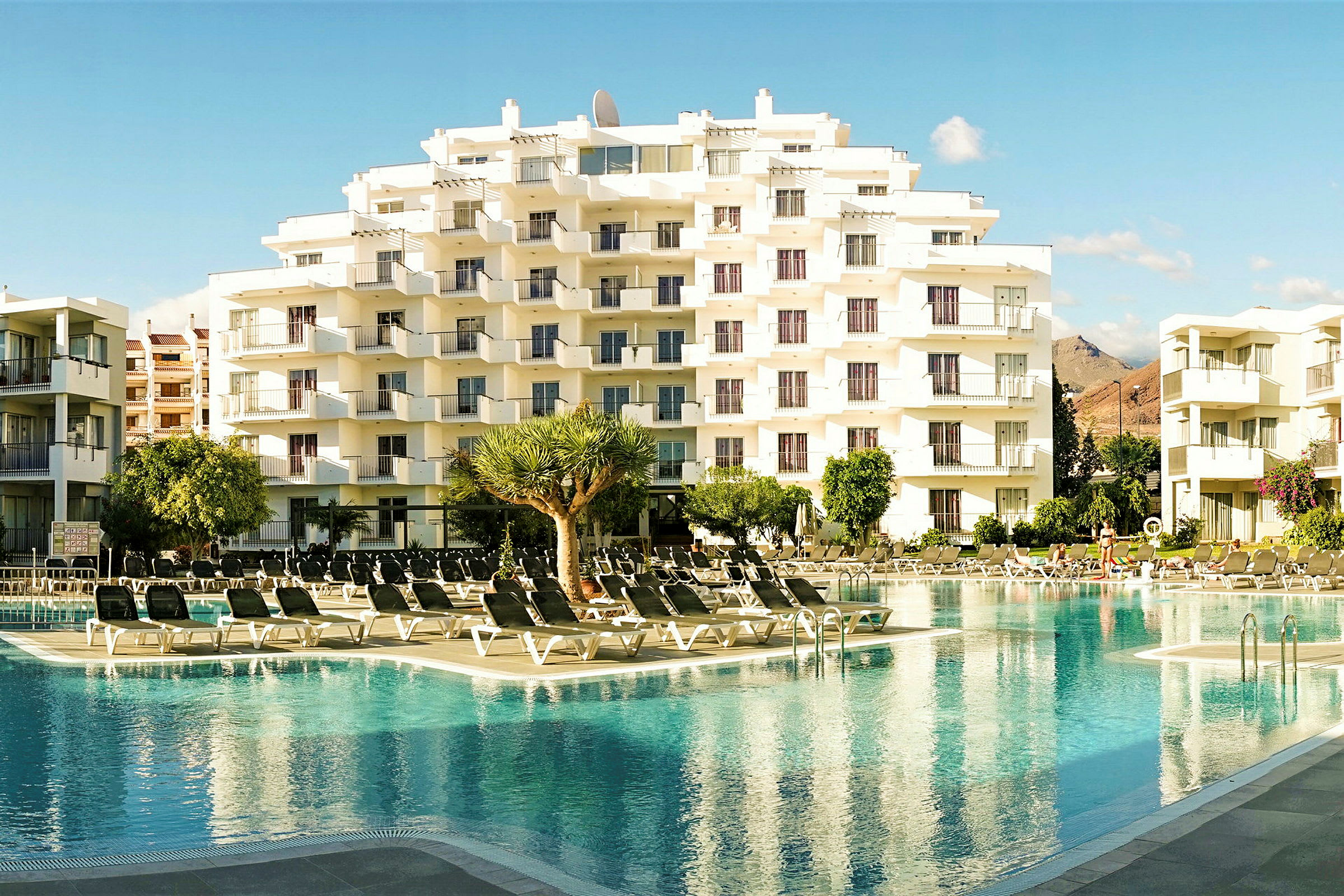Et hotel med flere etager ved siden af en pool. (AI-genereret tekst)