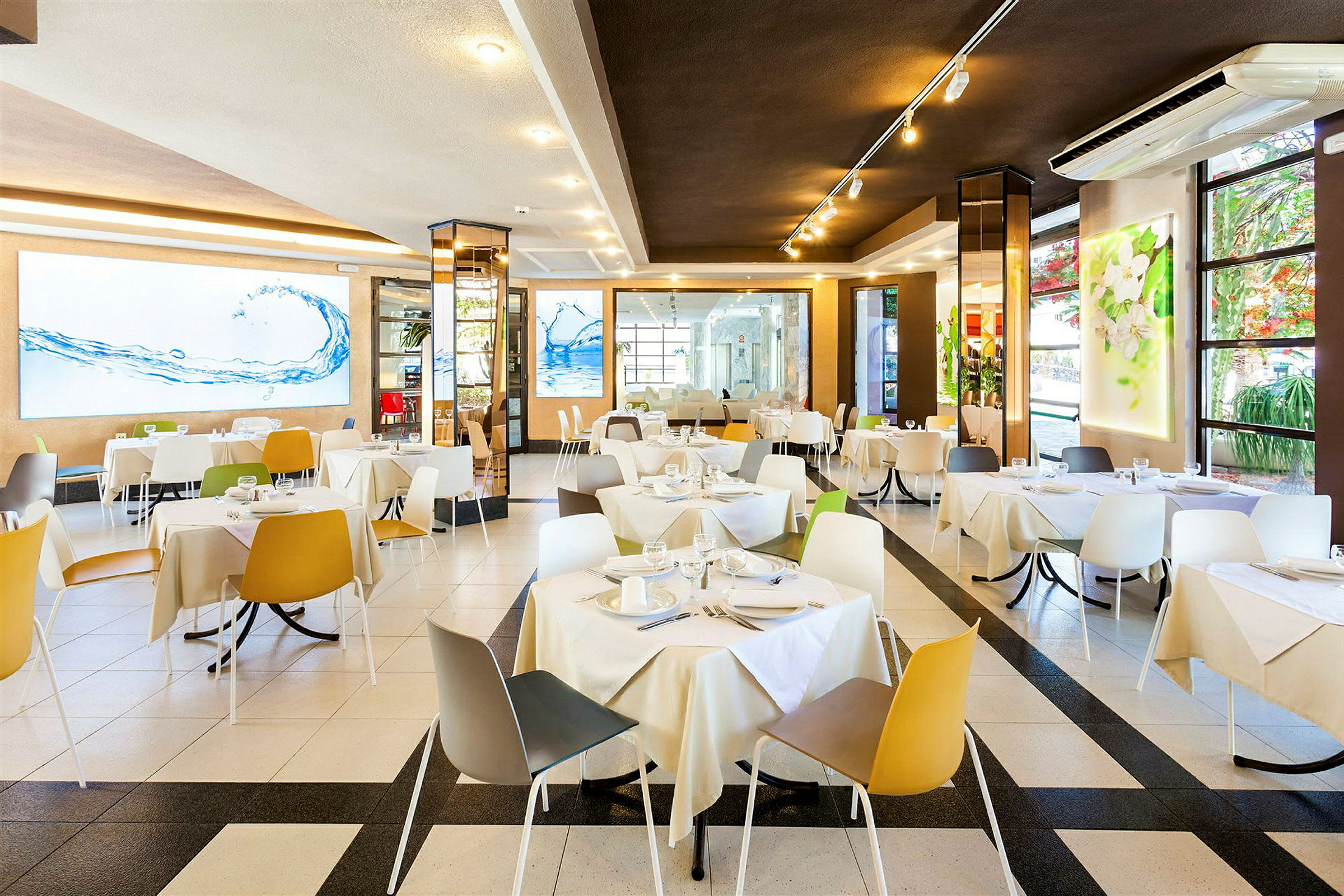Et lyst og moderne restaurantområde med borde og stole i forskellige farver. (AI-genereret tekst)