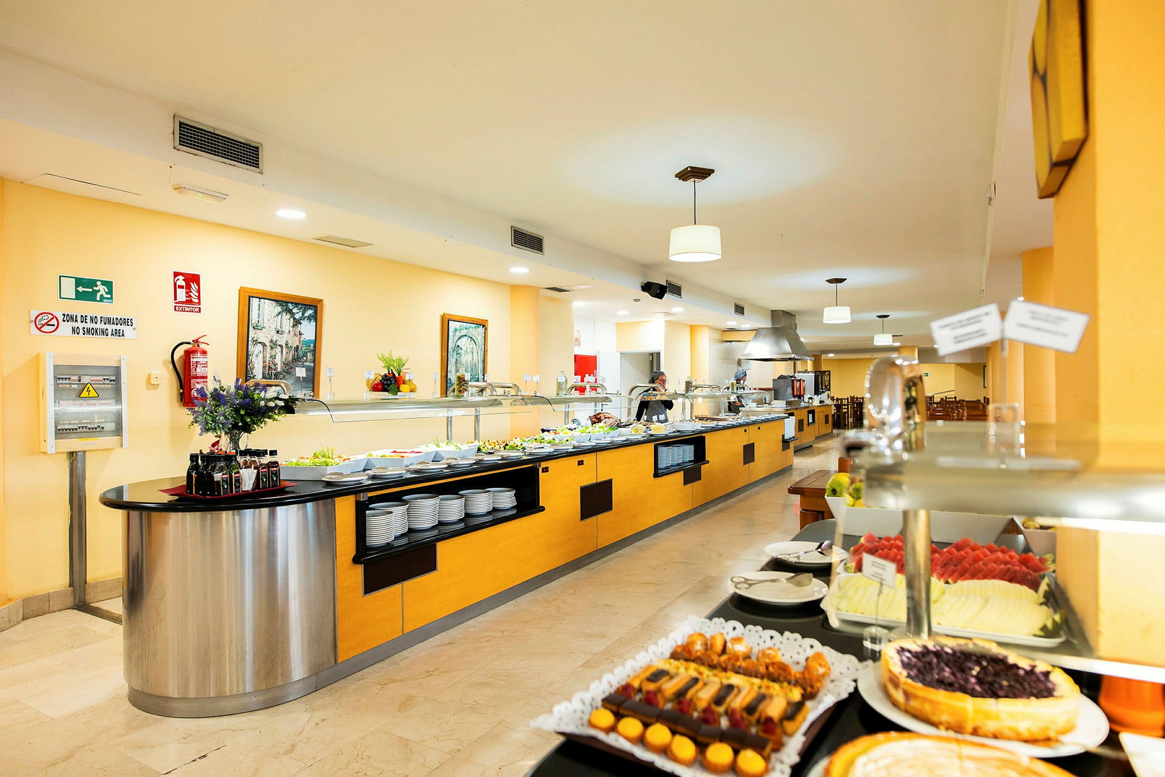 Et hotelbuffetområde med mad anrettet på lange serveringsborde. (AI-genereret tekst)