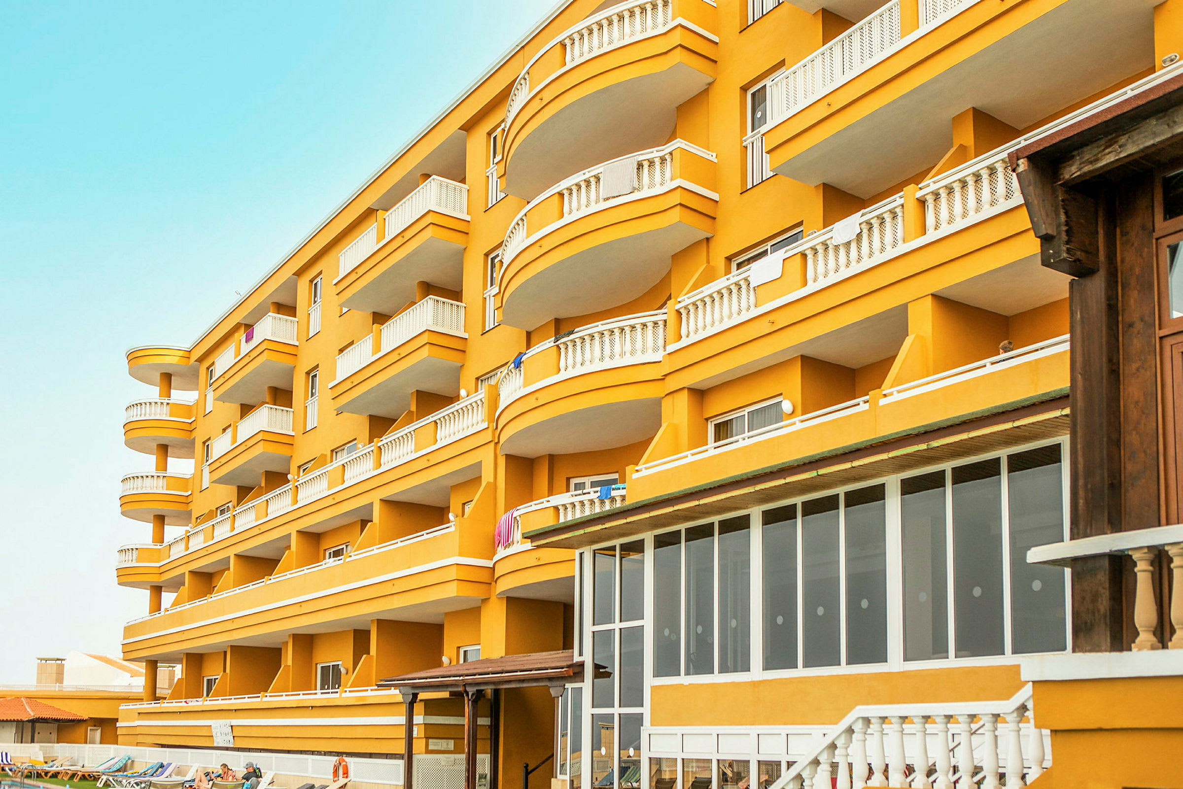 Et gult hotel med mange altaner i flere etager. (AI-genereret tekst)