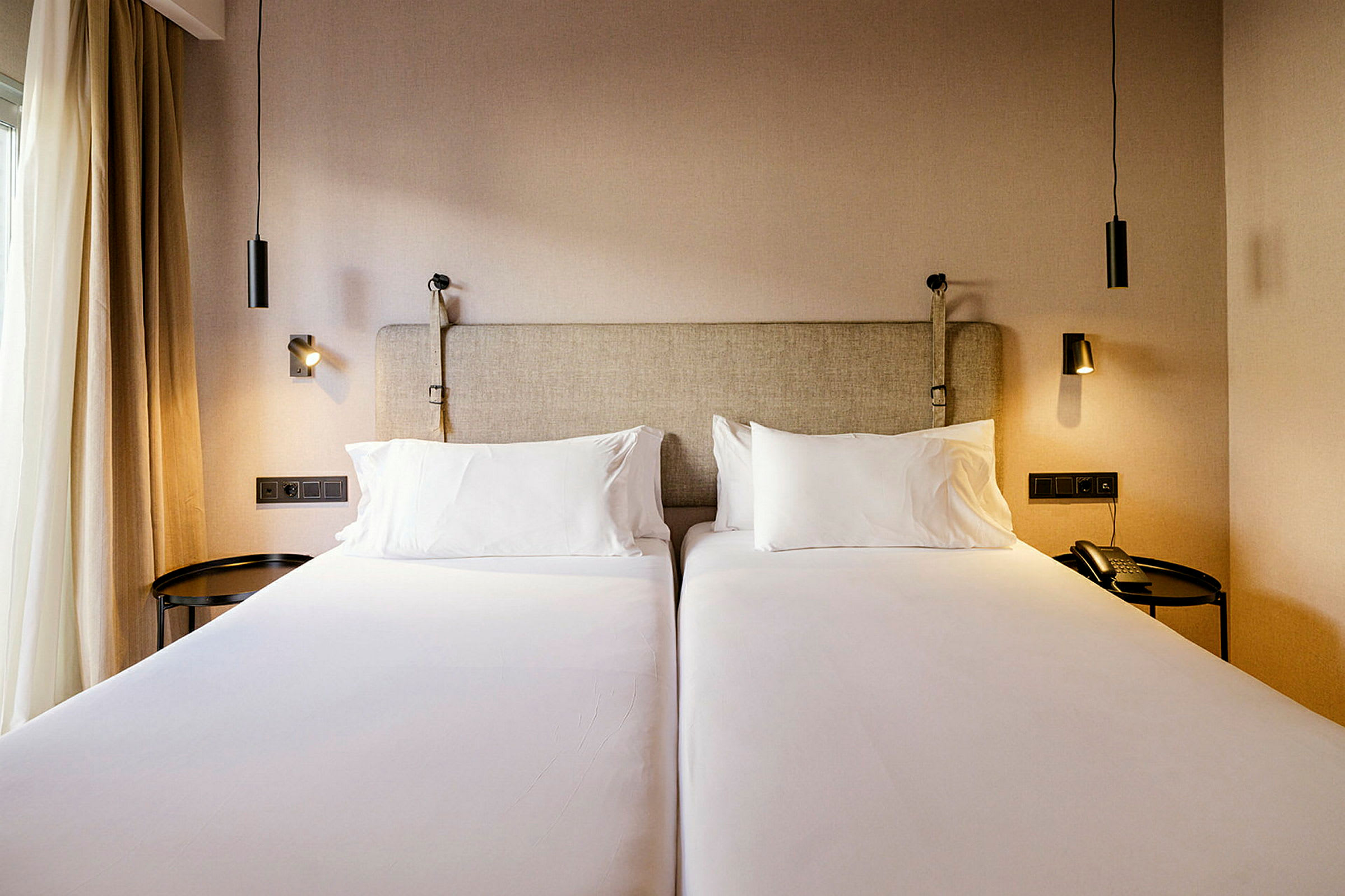 To enkeltsenge på et hotelværelse med sengelamper. (AI-genereret tekst)