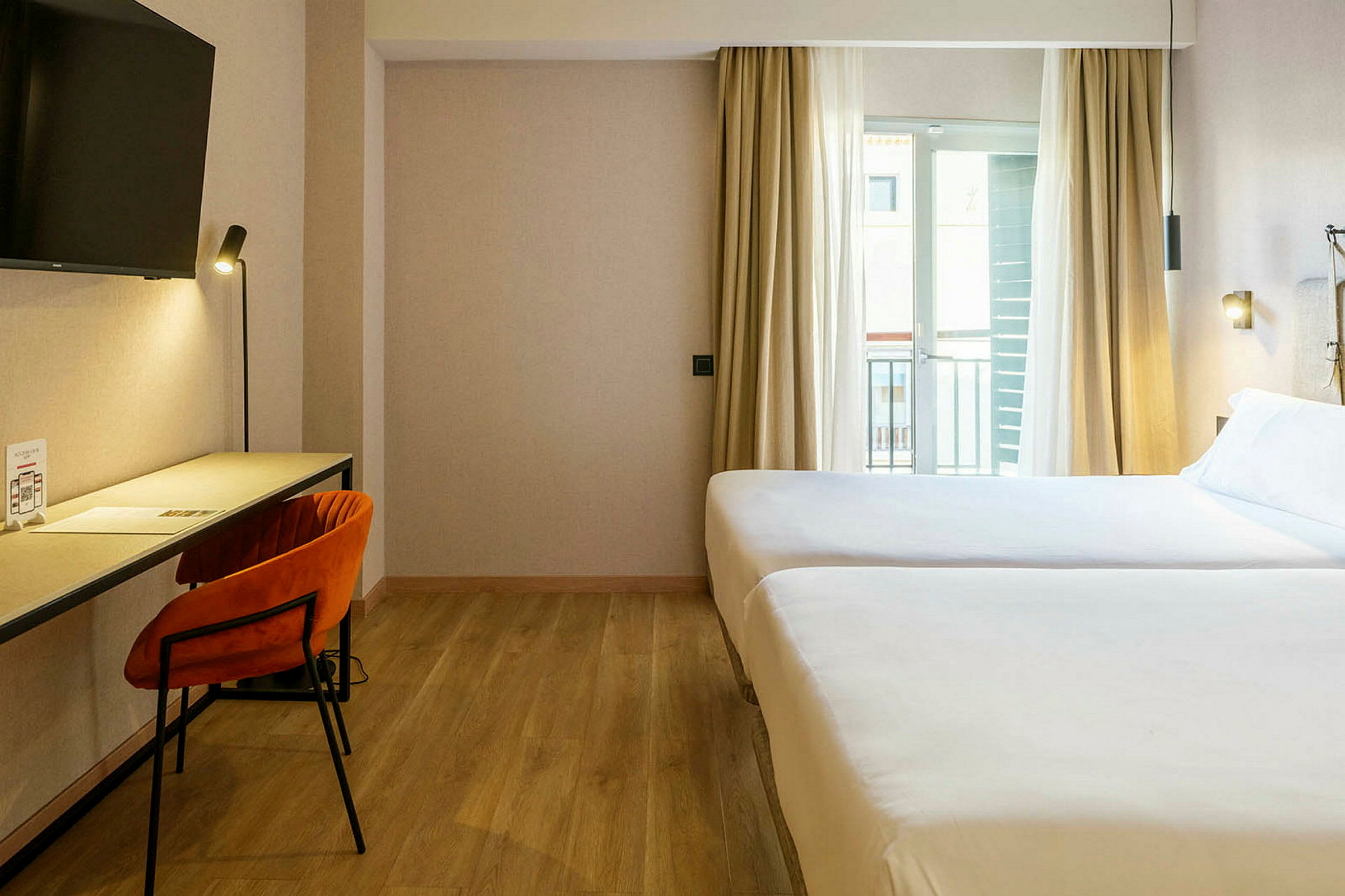 Et hotelværelse med to senge, skrivebord og stol. (AI-genereret tekst)